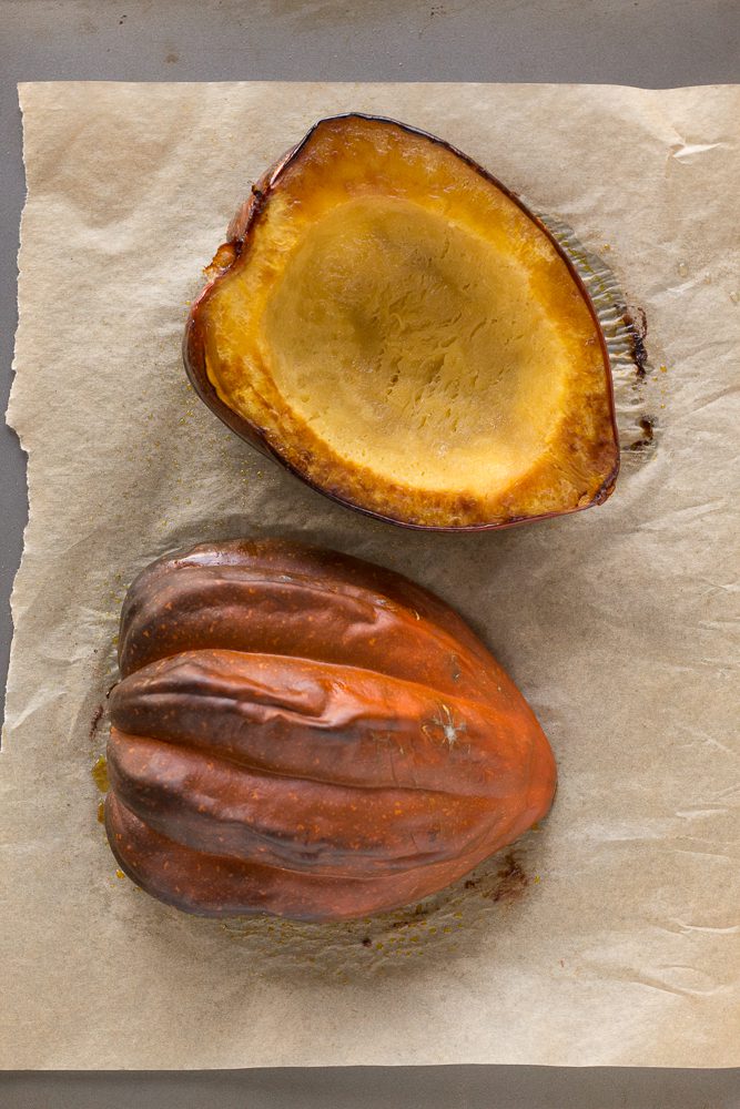 acorn squash halves roasted on parchment lined baking sheet by Flora & Vino
