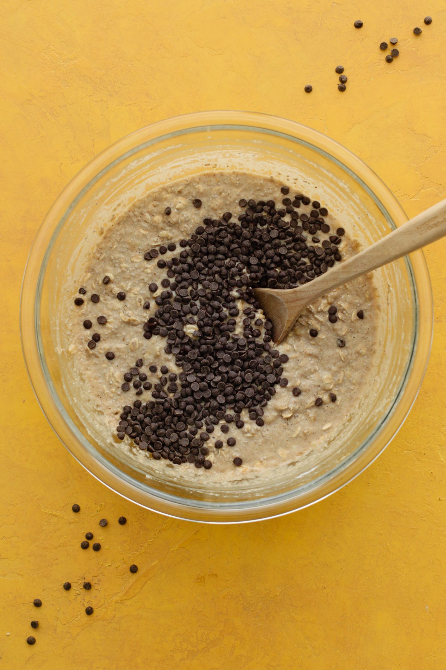 Banana Chia Chocolate Chip Muffin batter in bowl with chocolate chips and wooden spoon 
