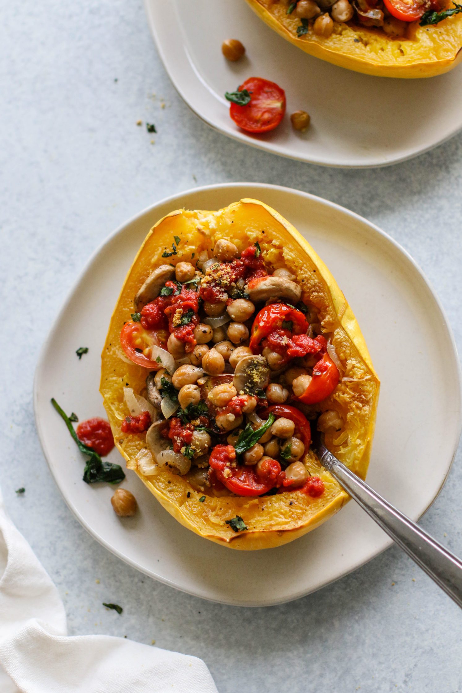 Italian Stuffed Spaghetti Squash served with Crispy Chickpeas on a plate with a fork by Flora & Vino