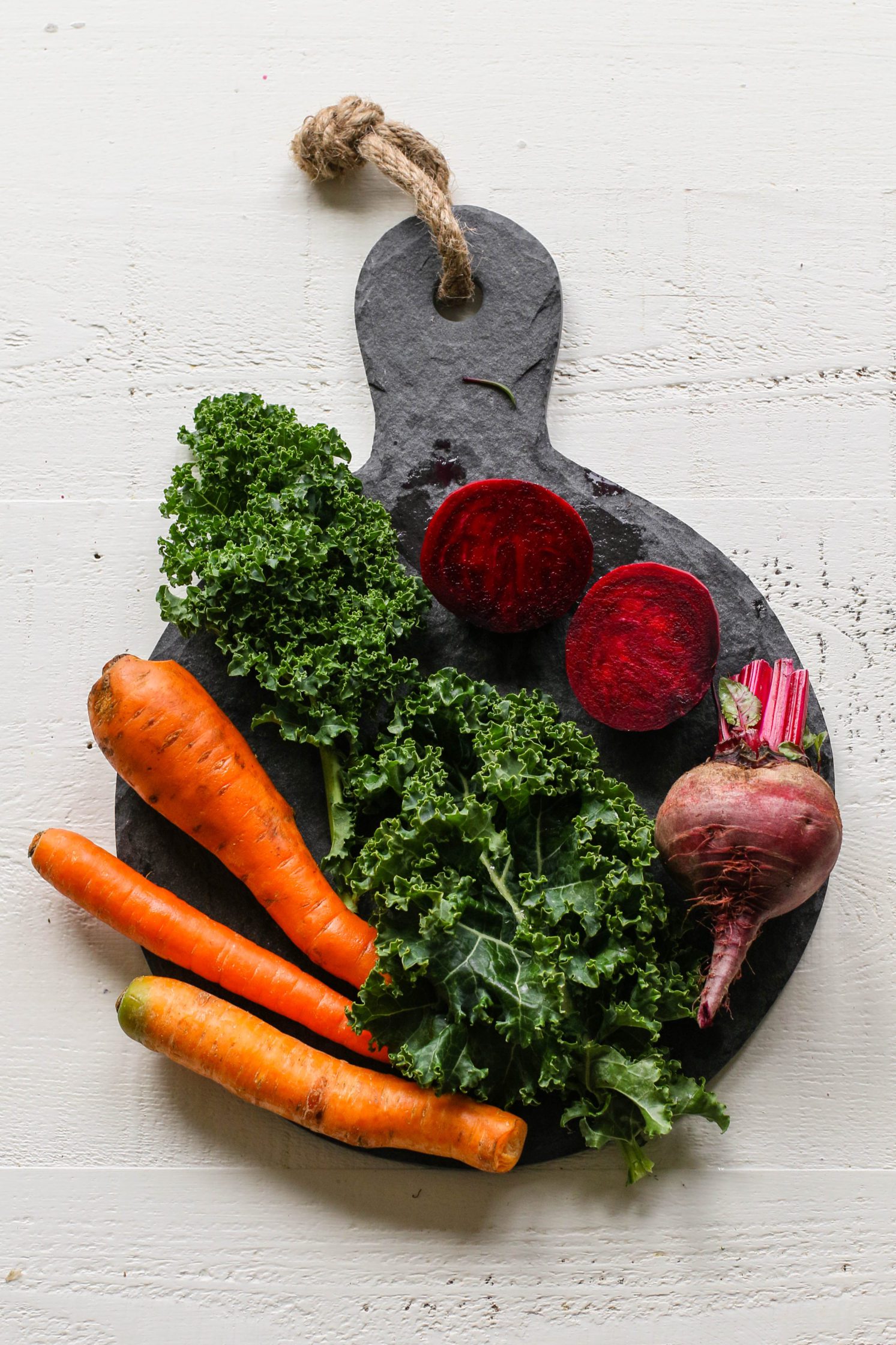 carrots, beets, and kale on a serving board by Flora & Vino