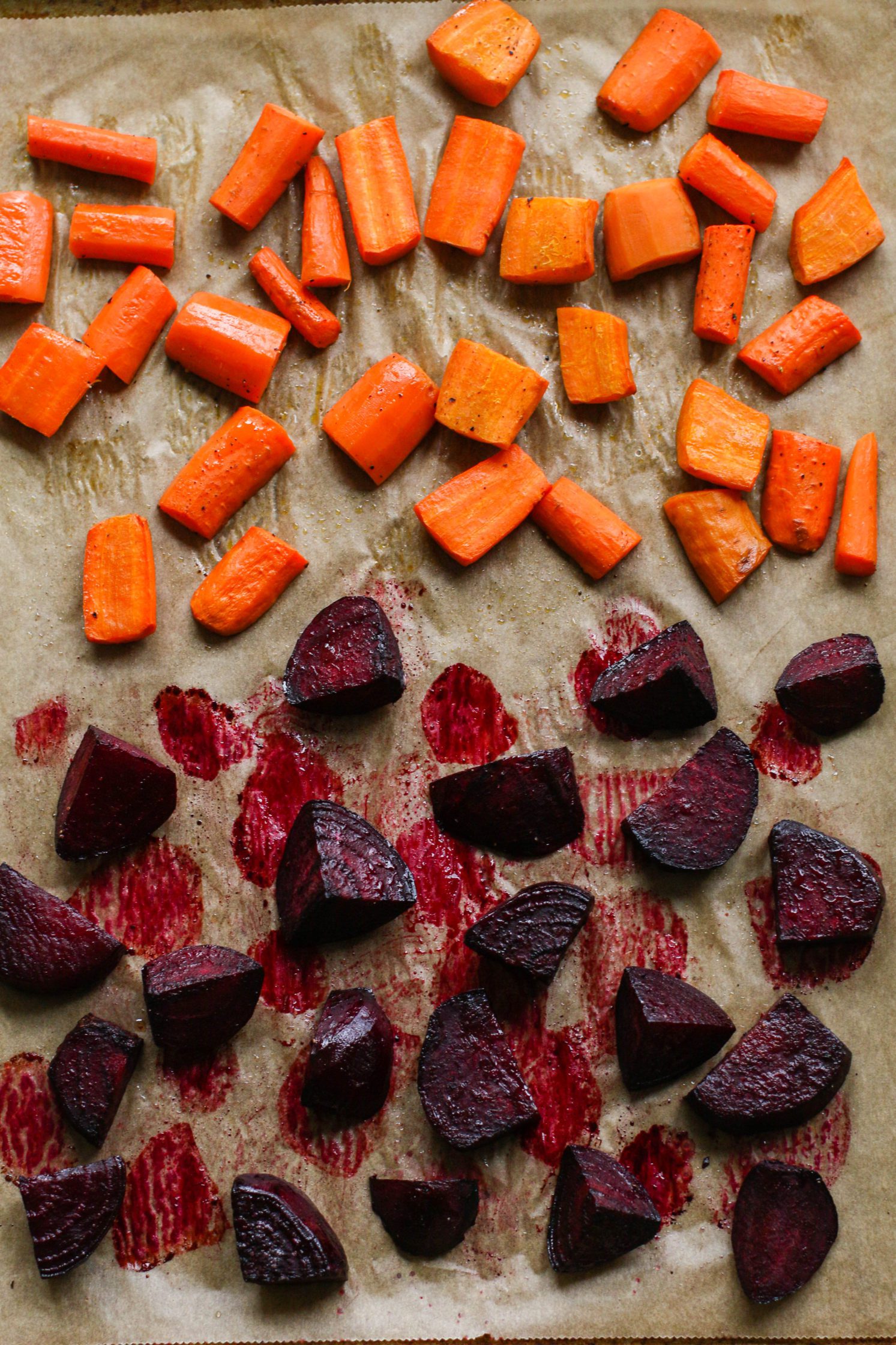 chopped carrots and beets with avocado oil on parchment lined baking sheet by Flora & Vino