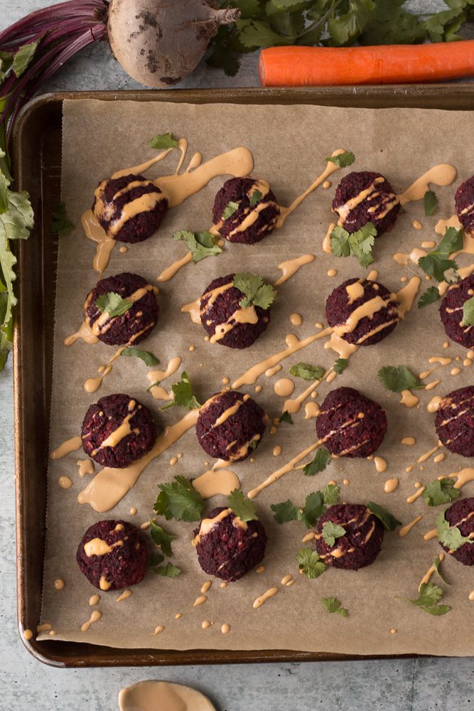 Lentil Walnut Beet Balls baked on parchment paper with Spicy Tahini Dressing by Flora & Vino