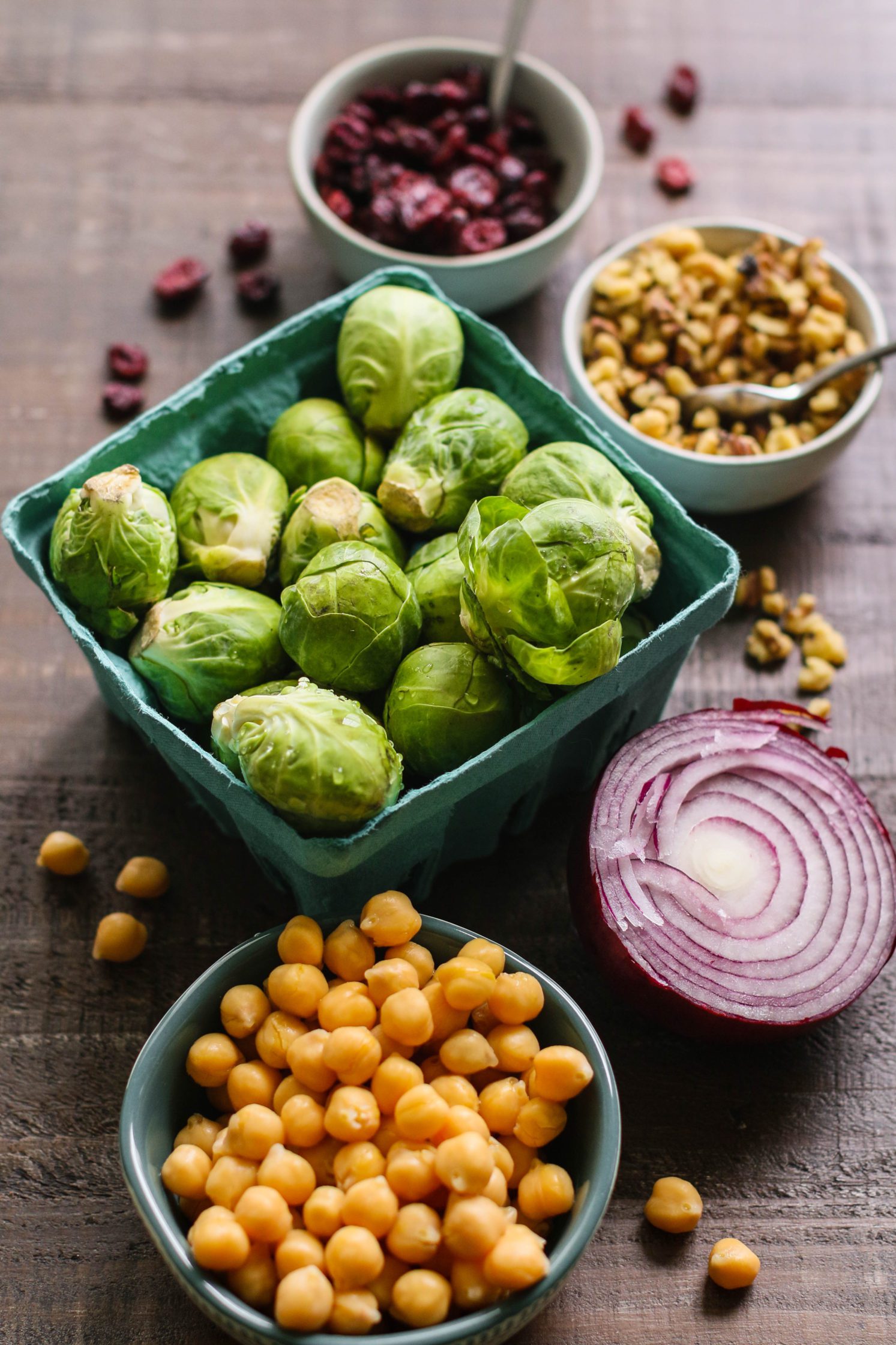 brussels sprouts, chickpeas, dried cranberries, pistachios, and red onion on wooden board by Flora & Vino