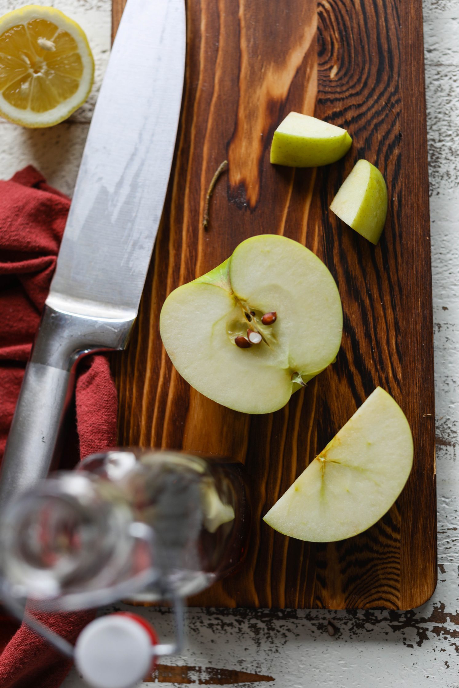 Apple sliced on a wooden board with a knife by Flora & Vino