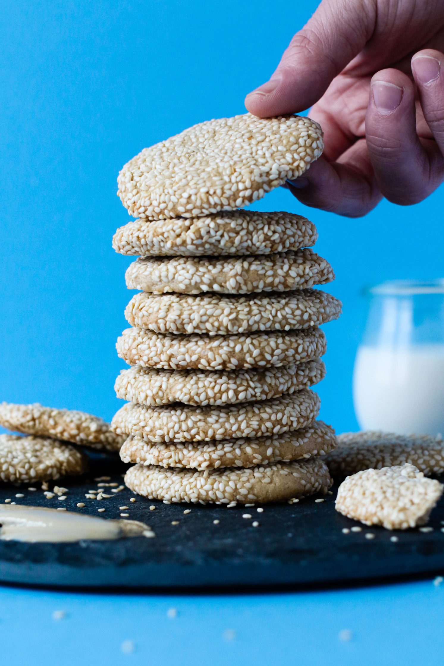 hand grabbing Maple Sesame Tahini Cookie from stack by Flora & Vino