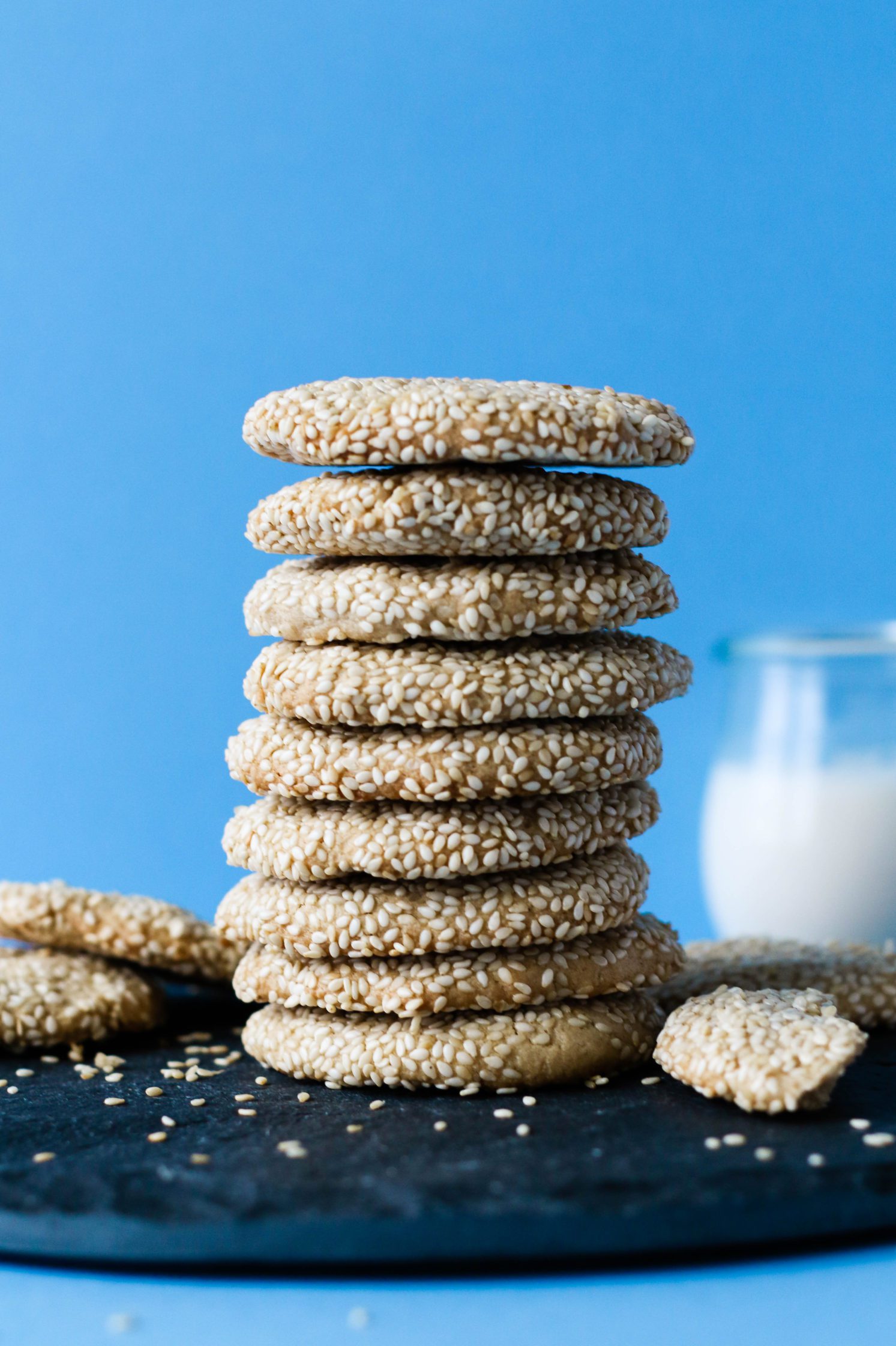 4 Ingredient Maple Sesame Tahini Cookies stacked on serving board with glass of milk by Flora & Vino