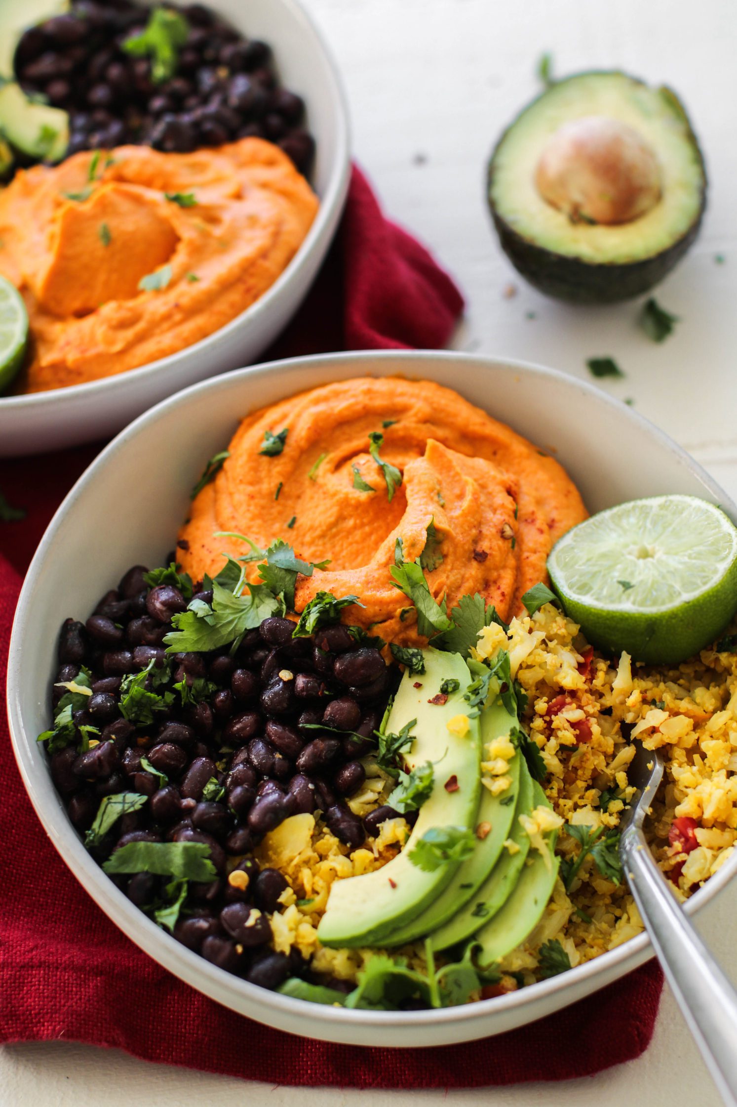 Smashed Burrito Bowls served in bowl with fork and red towel with avocado and lime