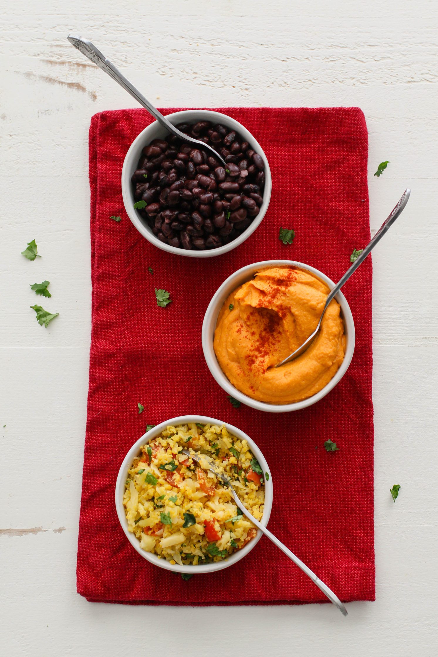 black beans, paprika sweet potato smash, and cauliflower rice in bowls on red towel