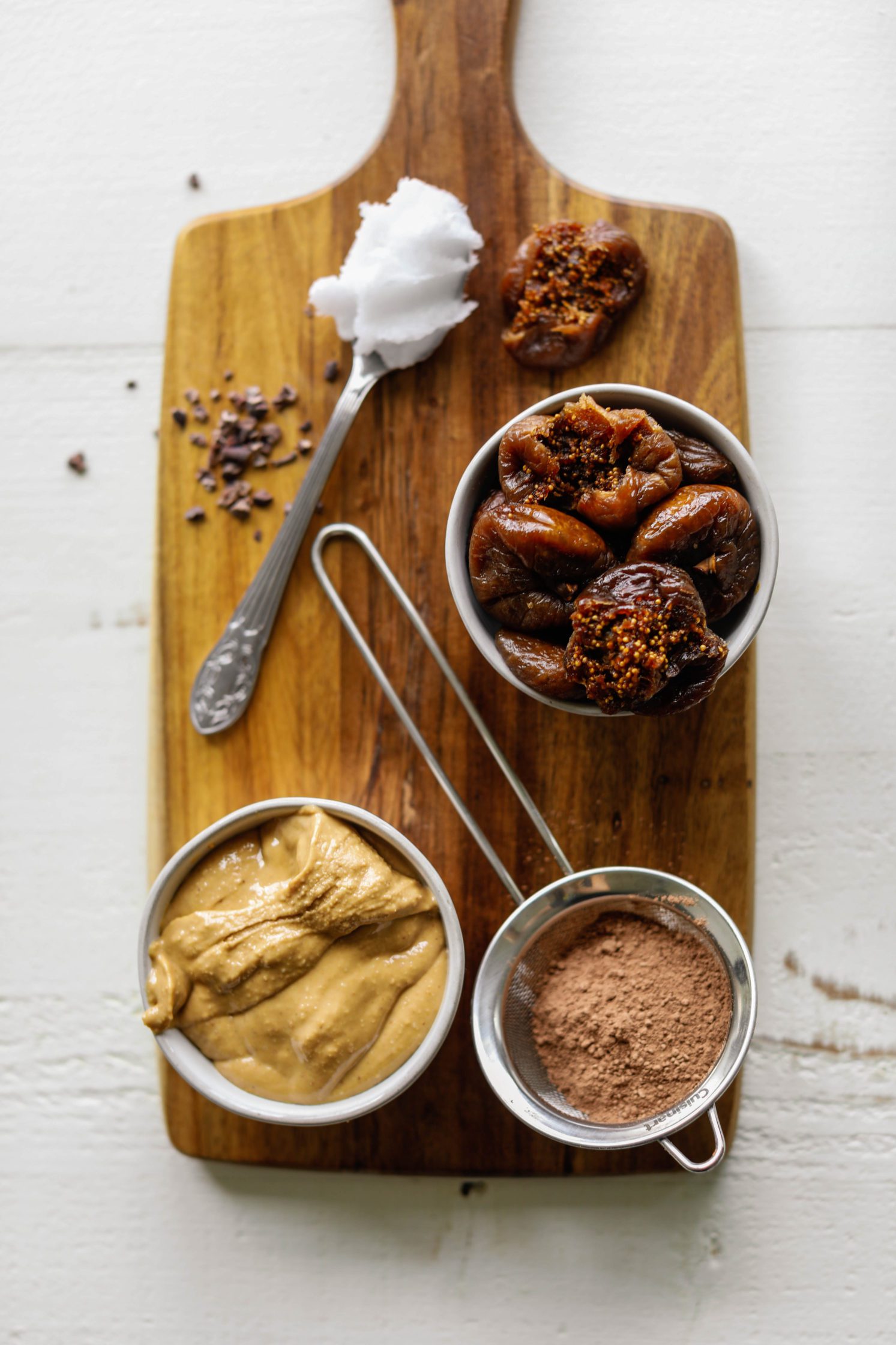nut butter, dried figs, cacao powder, and coconut oil on wooden board by Flora & Vino