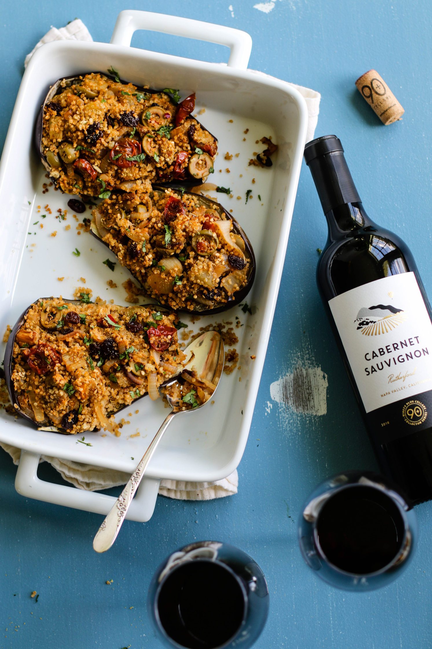 Quinoa Stuffed Eggplant served in casserole dish with glasses of Cabernet Sauvignon by Flora & Vino