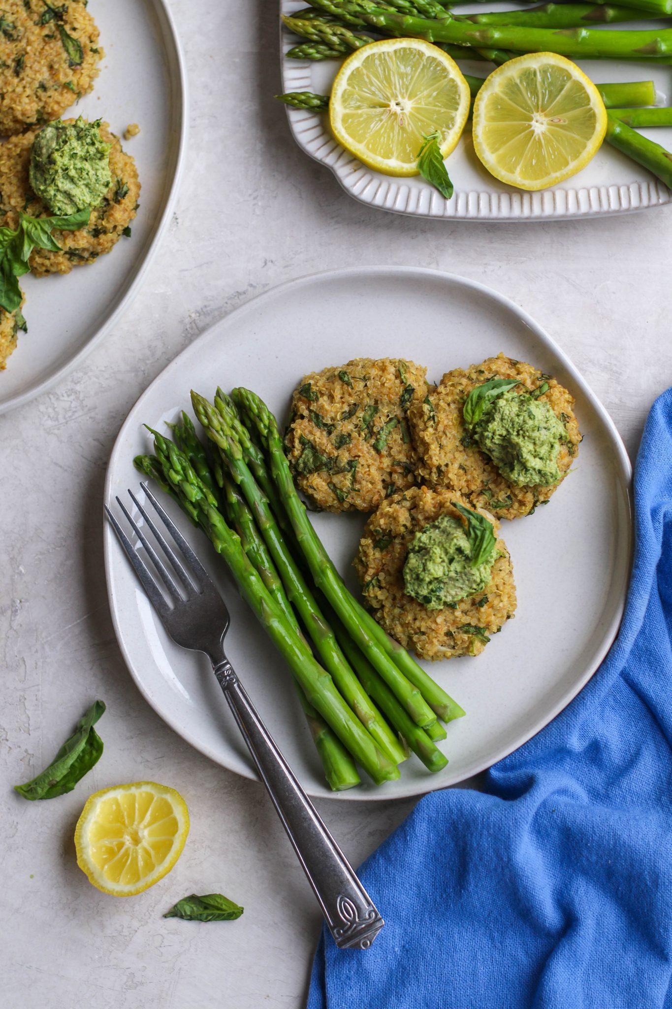 Quinoa Cakes with Basil Pesto served on plate with asparagus and a fork by Flora & Vino