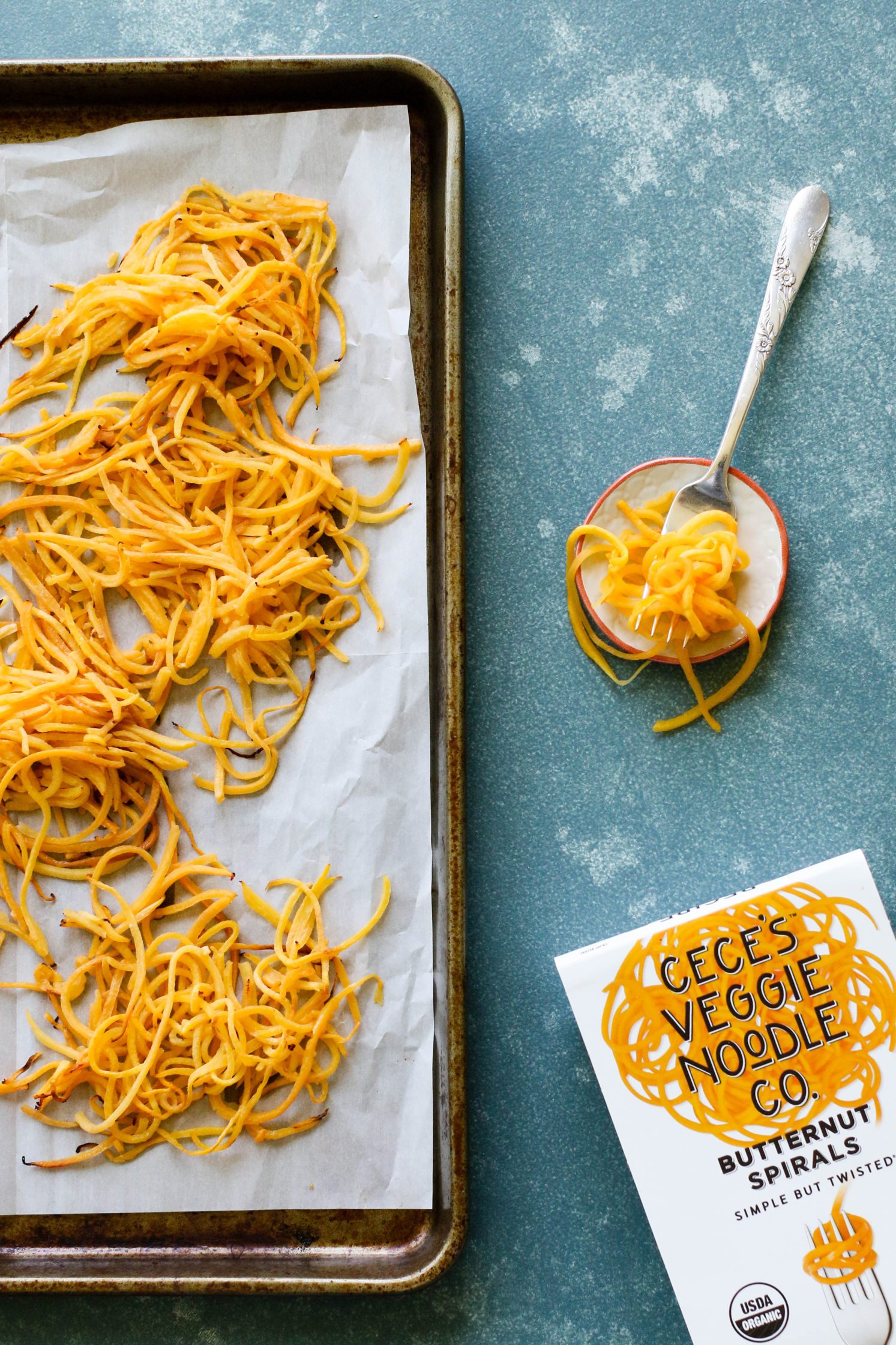 baked butternut squash noodles on a parchment lined baking sheet