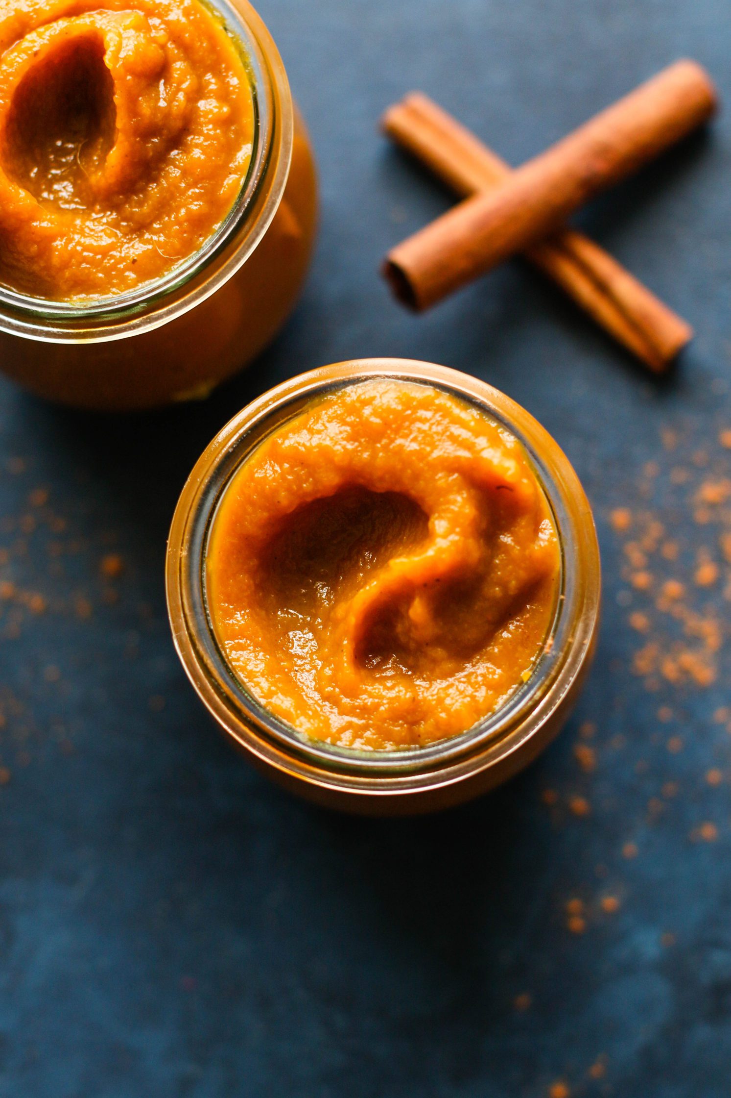 Low Sugar Pumpkin Apple Butter served in Weck jars on blue board with cinnamon sticks on the side