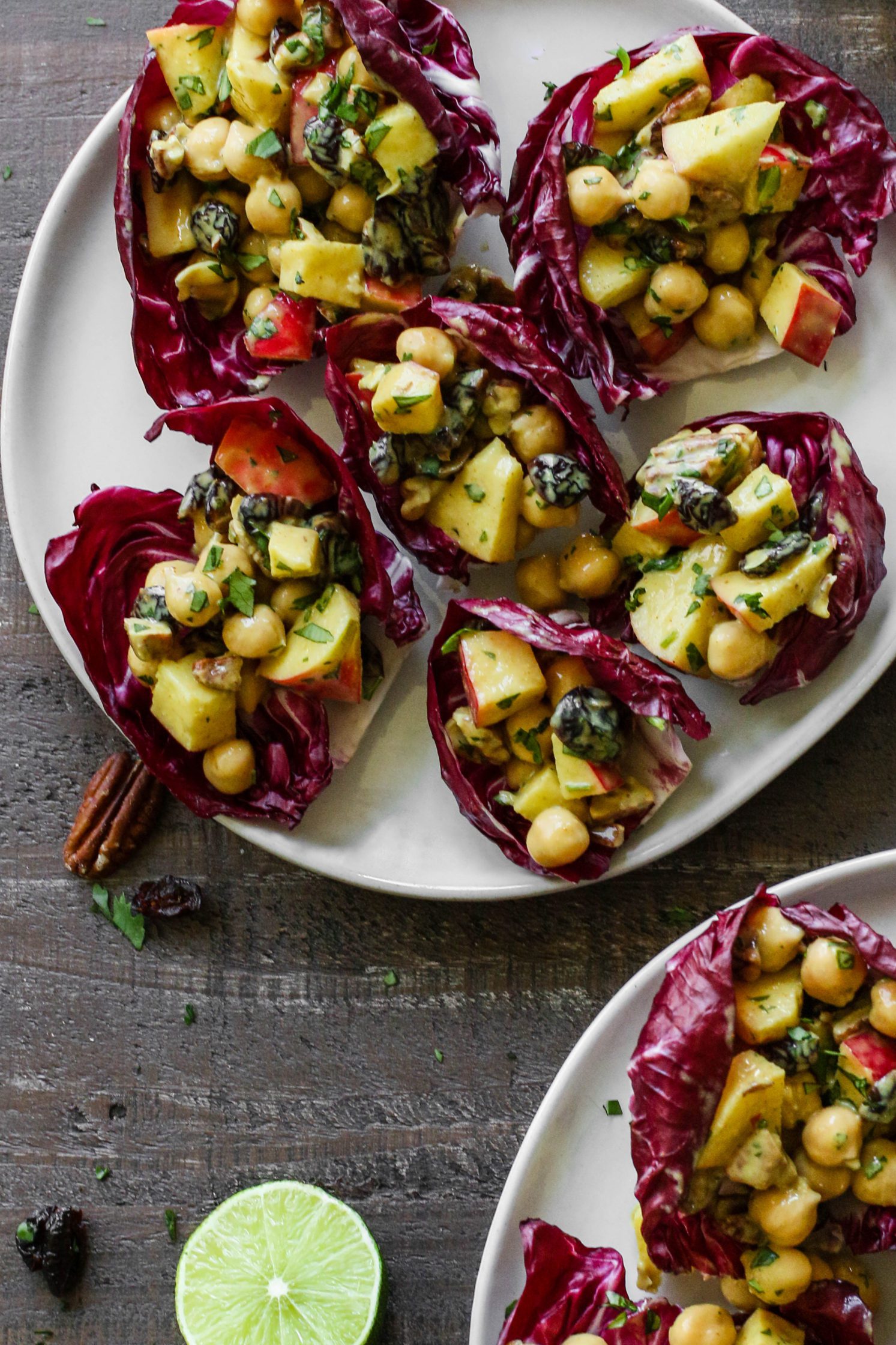 Curried Cranberry Apple Chickpea Salad served in radicchio leaves on a plate by Flora & Vino