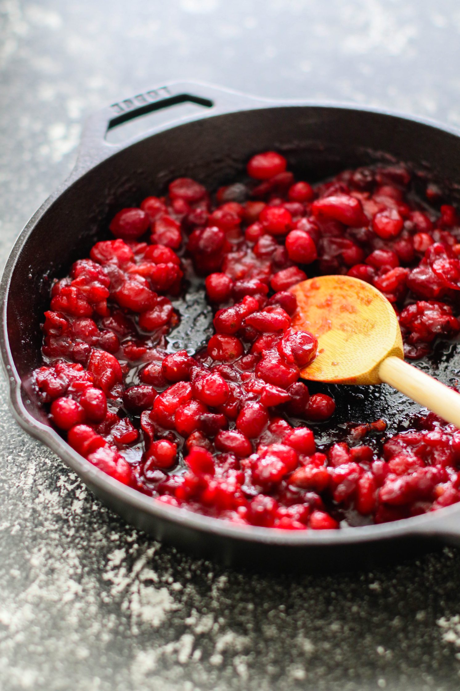 Orange Cranberry Sauce in skillet with wooden spoon by Flora & Vino