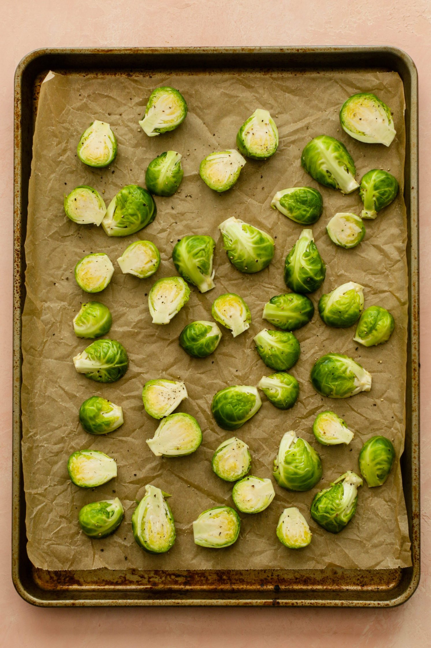 raw brussels sprouts on parchment lined baking sheet by Flora & Vino