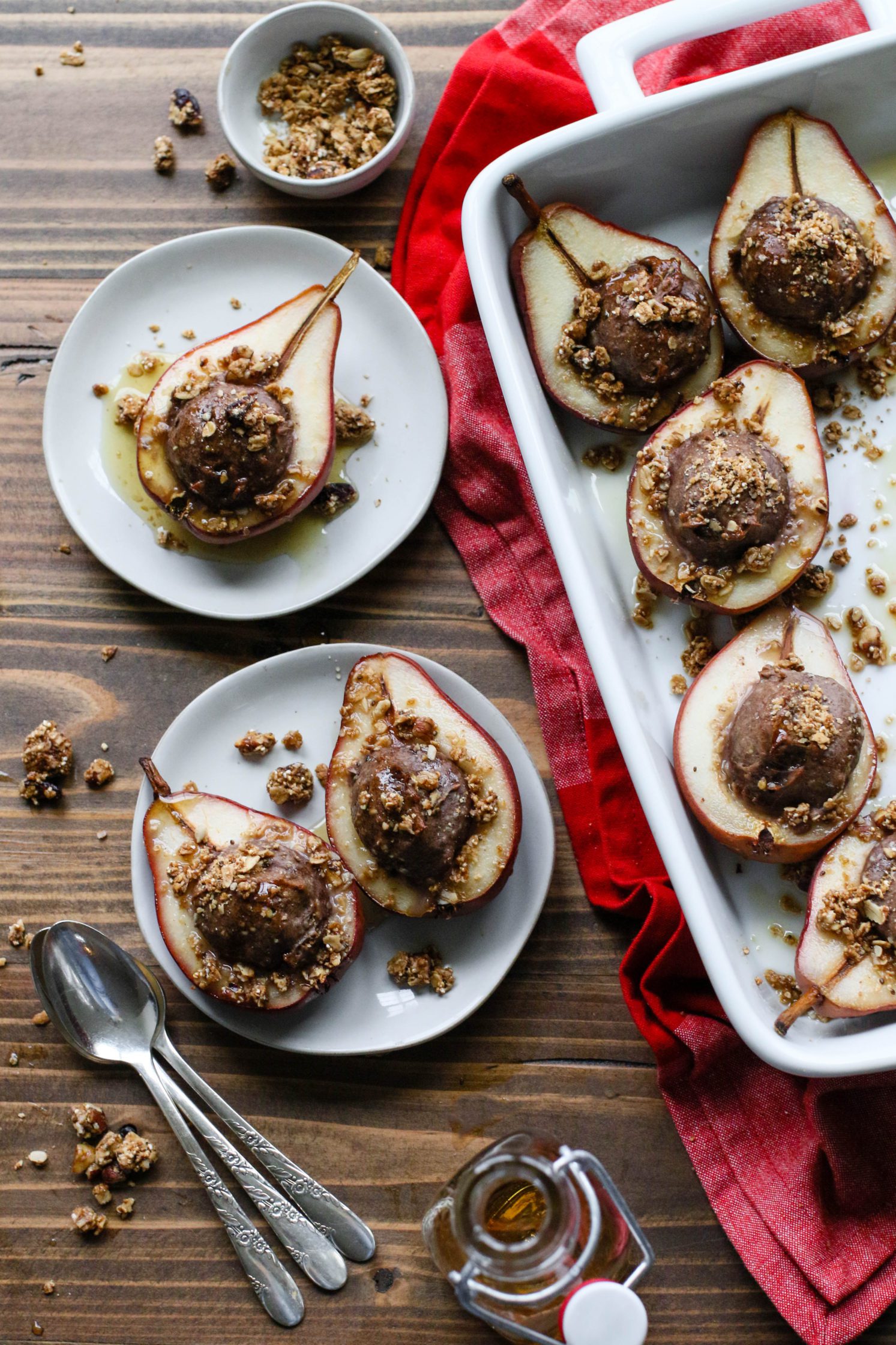 Nutty Protein Stuffed Pears served on plates with baking dish and spoons by Flora & Vino