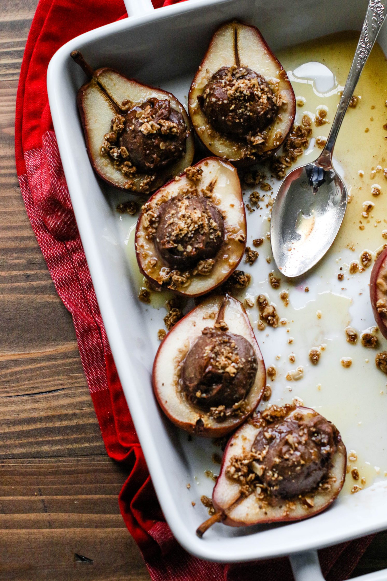 Nutty Protein Stuffed Pears in baking dish with a spoon by Flora & vino
