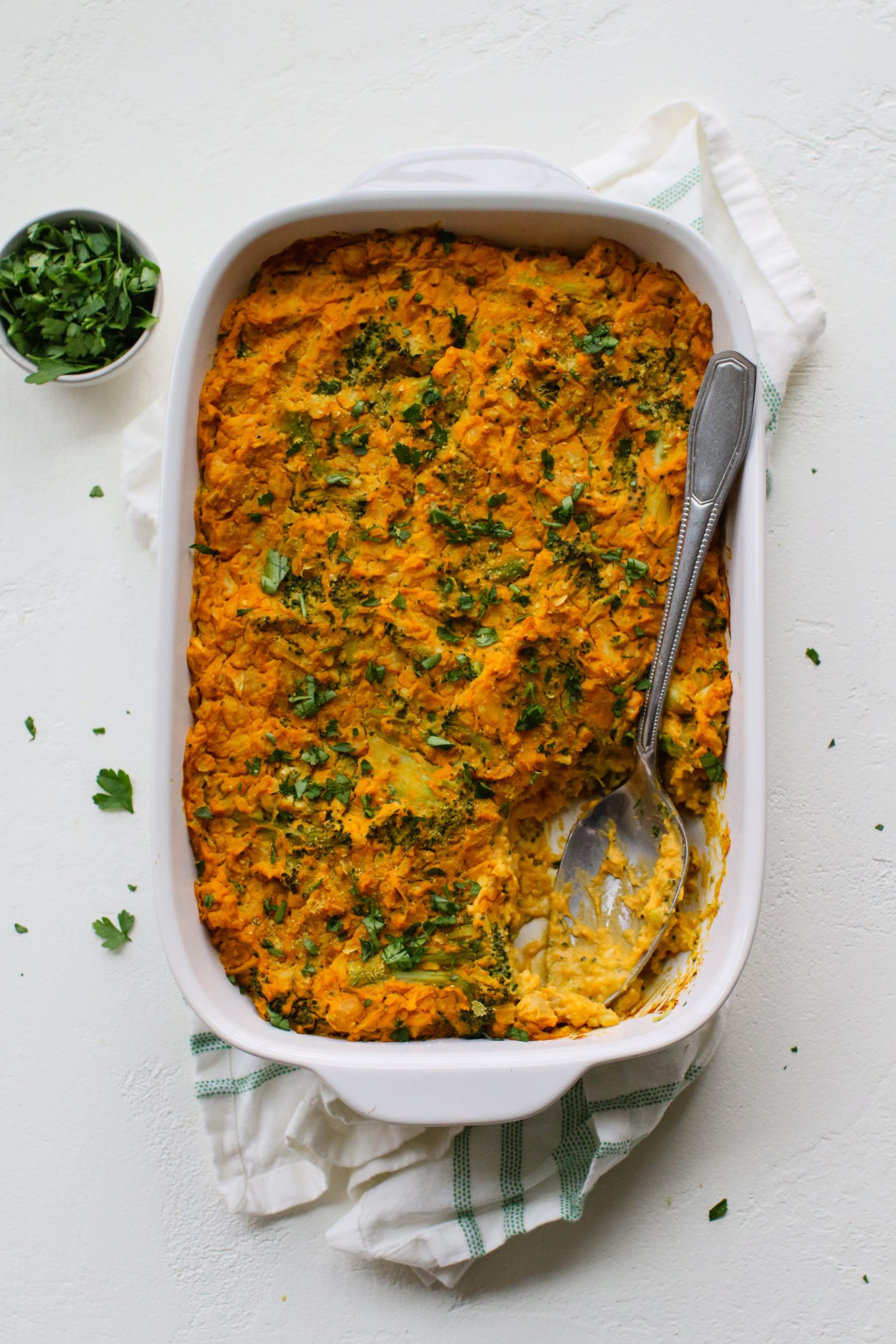 “Cheezy” Chickpea & Broccoli Casserole in casserole dish with spoon by Flora & Vino