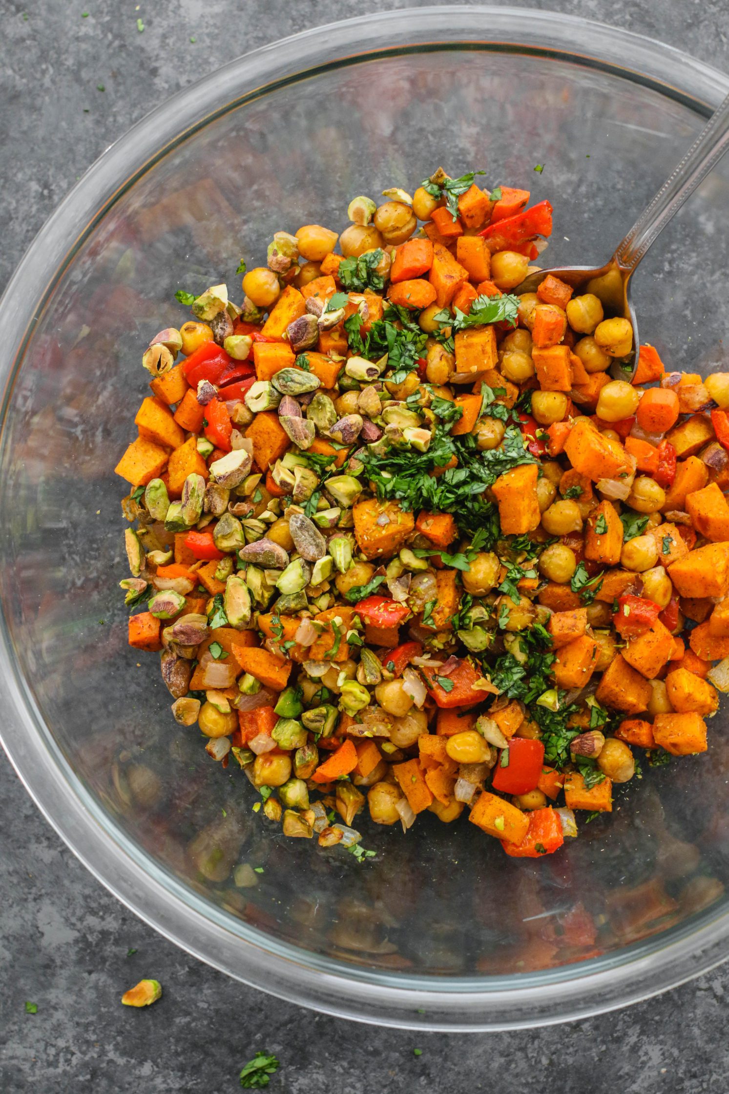 Warm Spiced Sweet Potato Salad in mixing bowl with with Pistachios and cilantro by Flora & vino