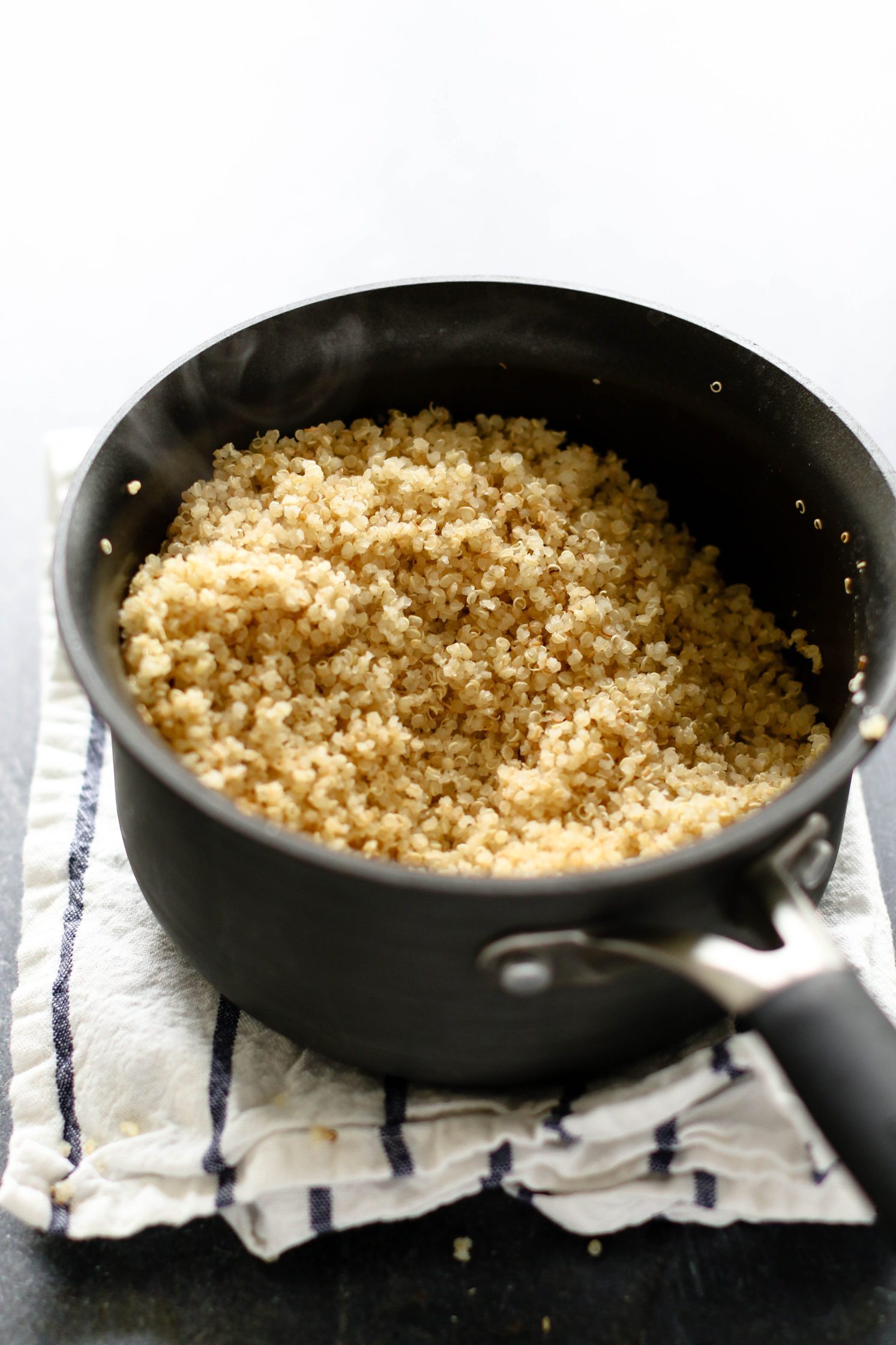toasted quinoa in large sauce pot on top of white and blue striped towel