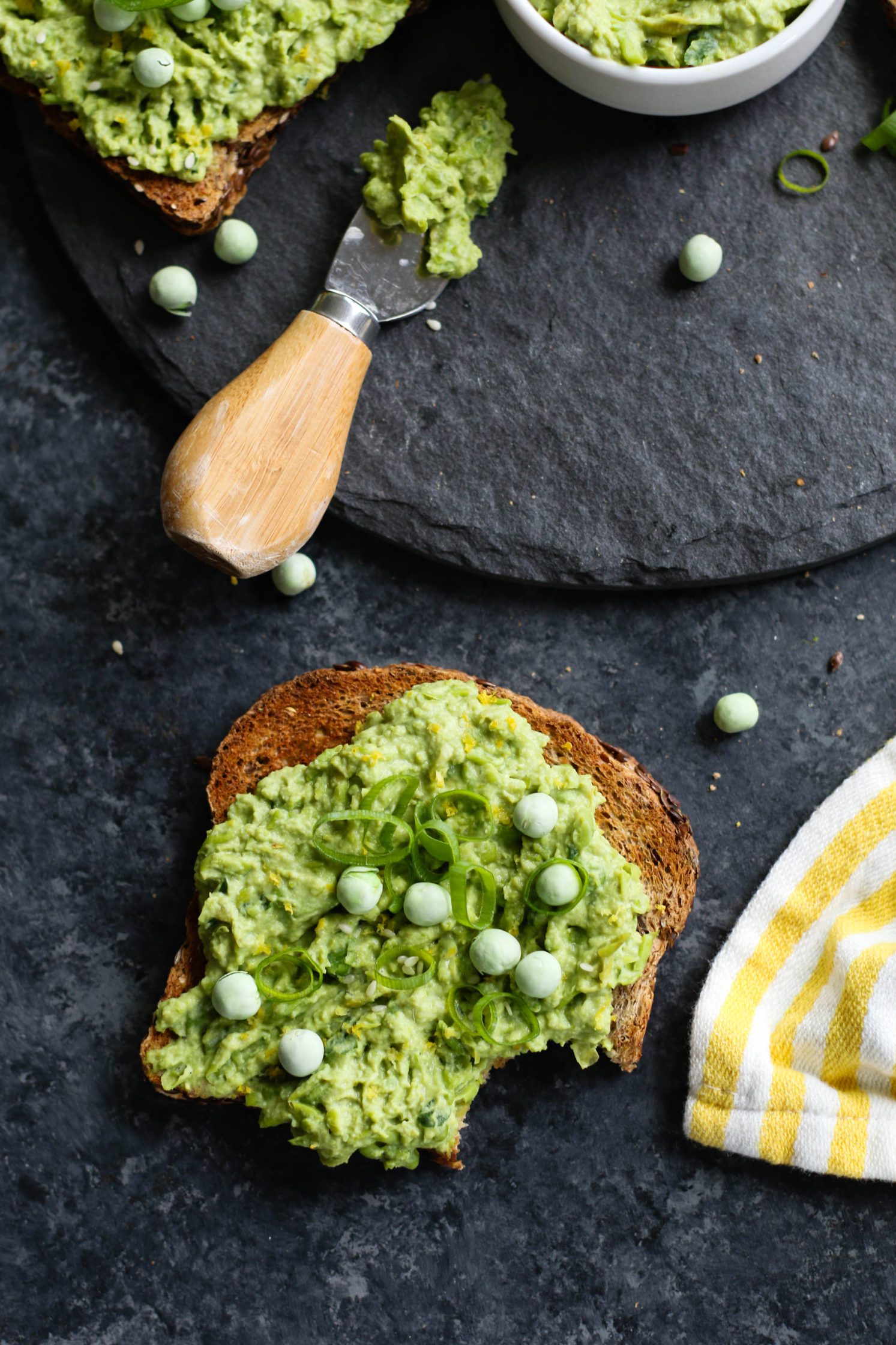 bite out of one toast with lemon-y smashed pea spread