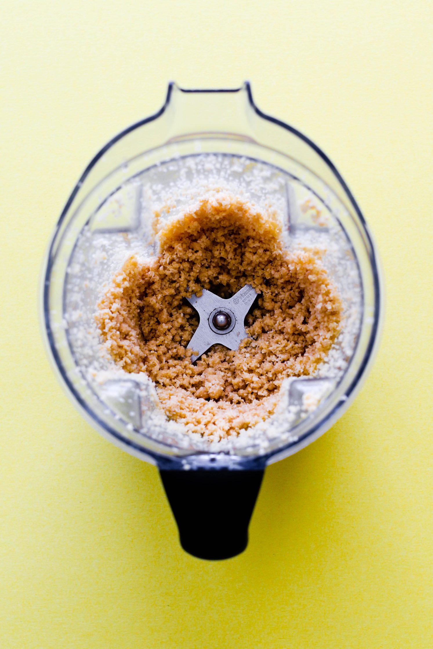 Coco-Roon crust pulsed in Vitamix blender on yellow background