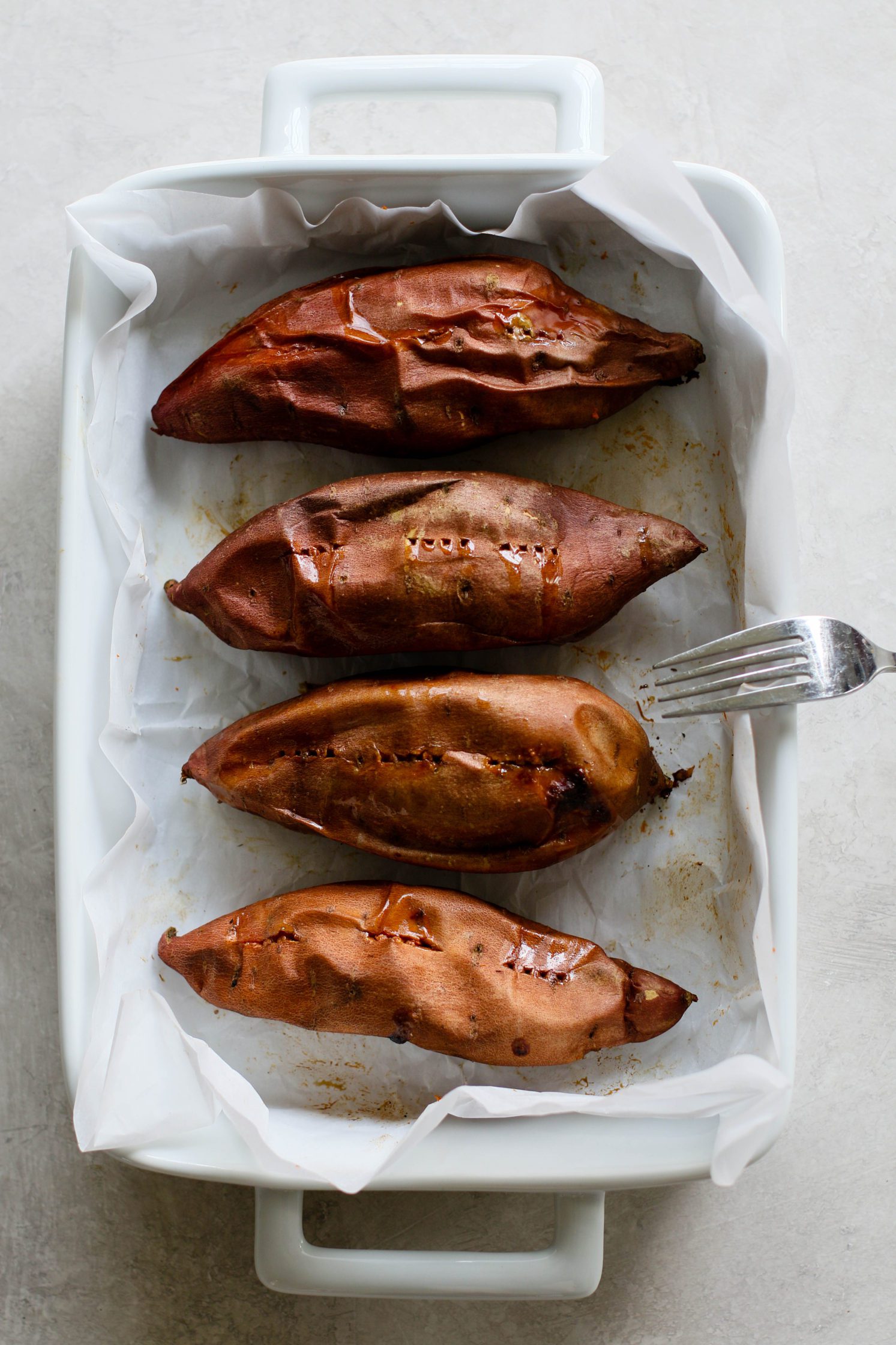 sweet potatoes baked in parchment lined baking dish by Flora & Vino