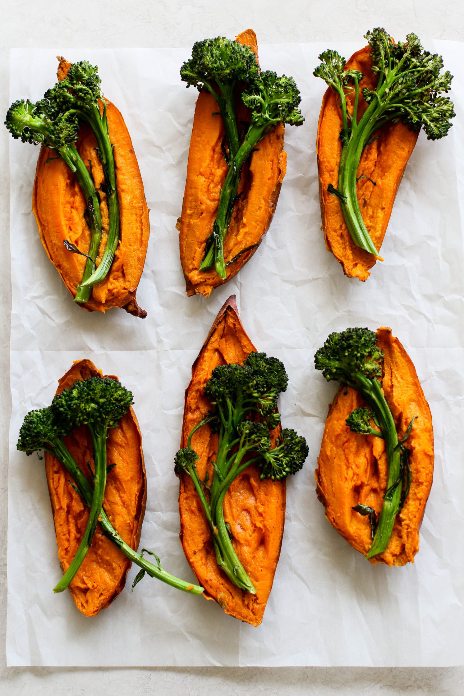 Sweet Potato Boats baked topped with roasted broccoli on parchment paper by Flora & Vino