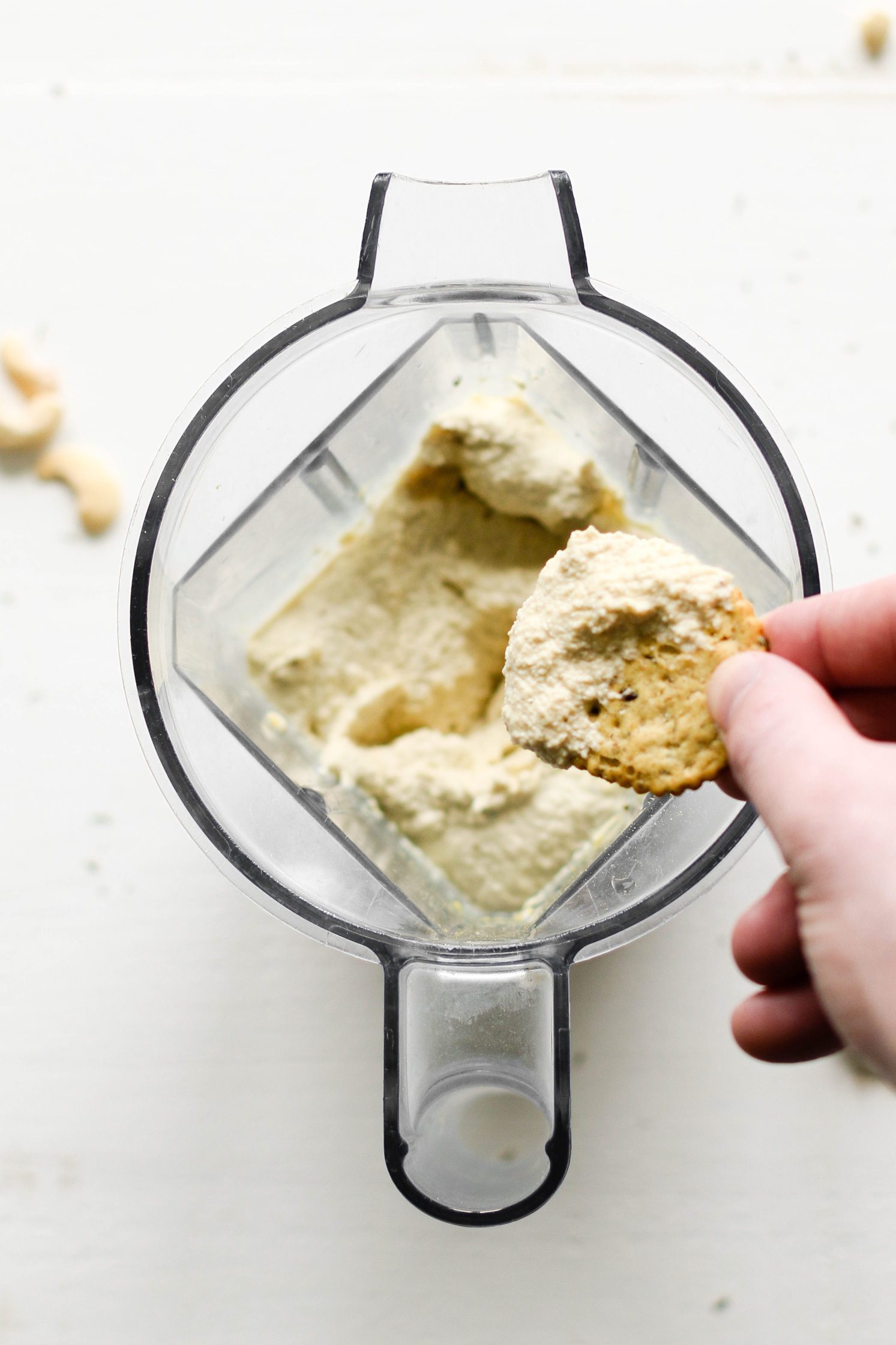 Easy Raw Cashew Cheese blended in Vitamix with hand dipping chip in by Flora & Vino