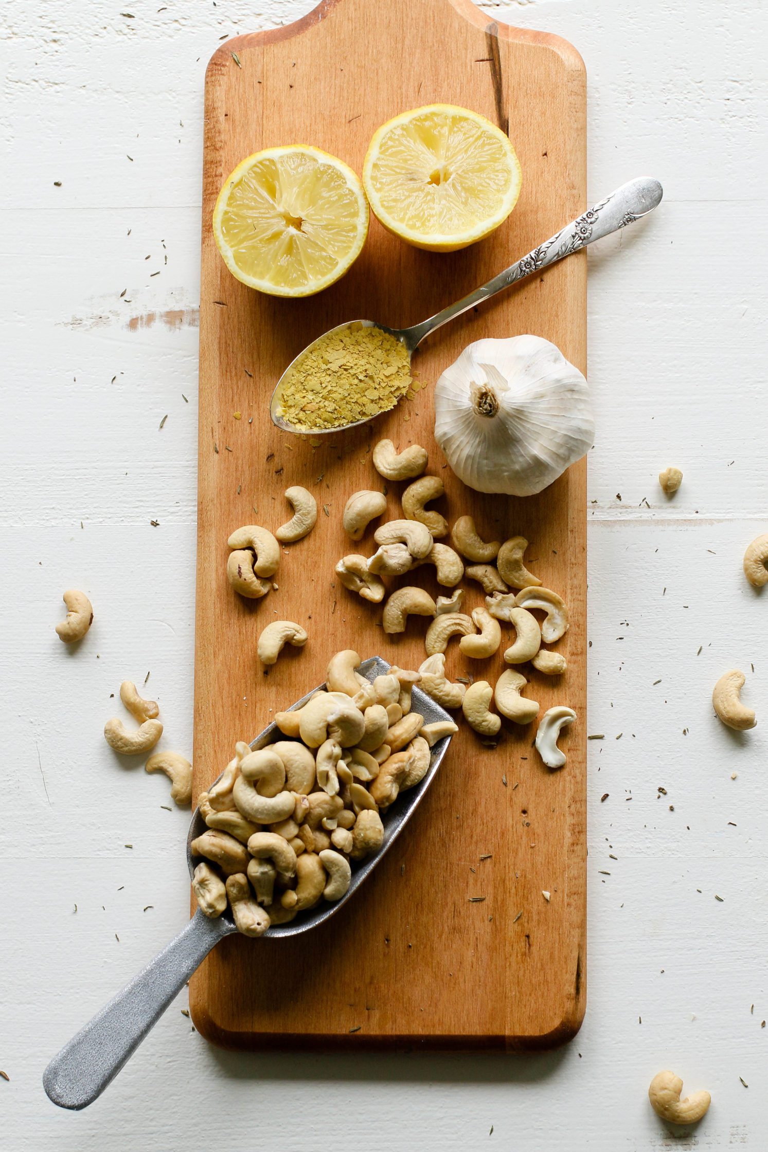 cashews, garlic, nutritional yeast, and lemon on wooden serving board by Flora & Vino