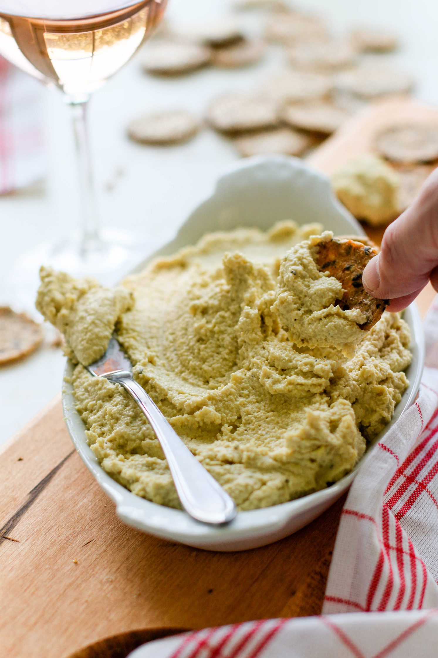 hand dipping into Easy Cashew Cheese served with glass of Rosé by Flora & Vino