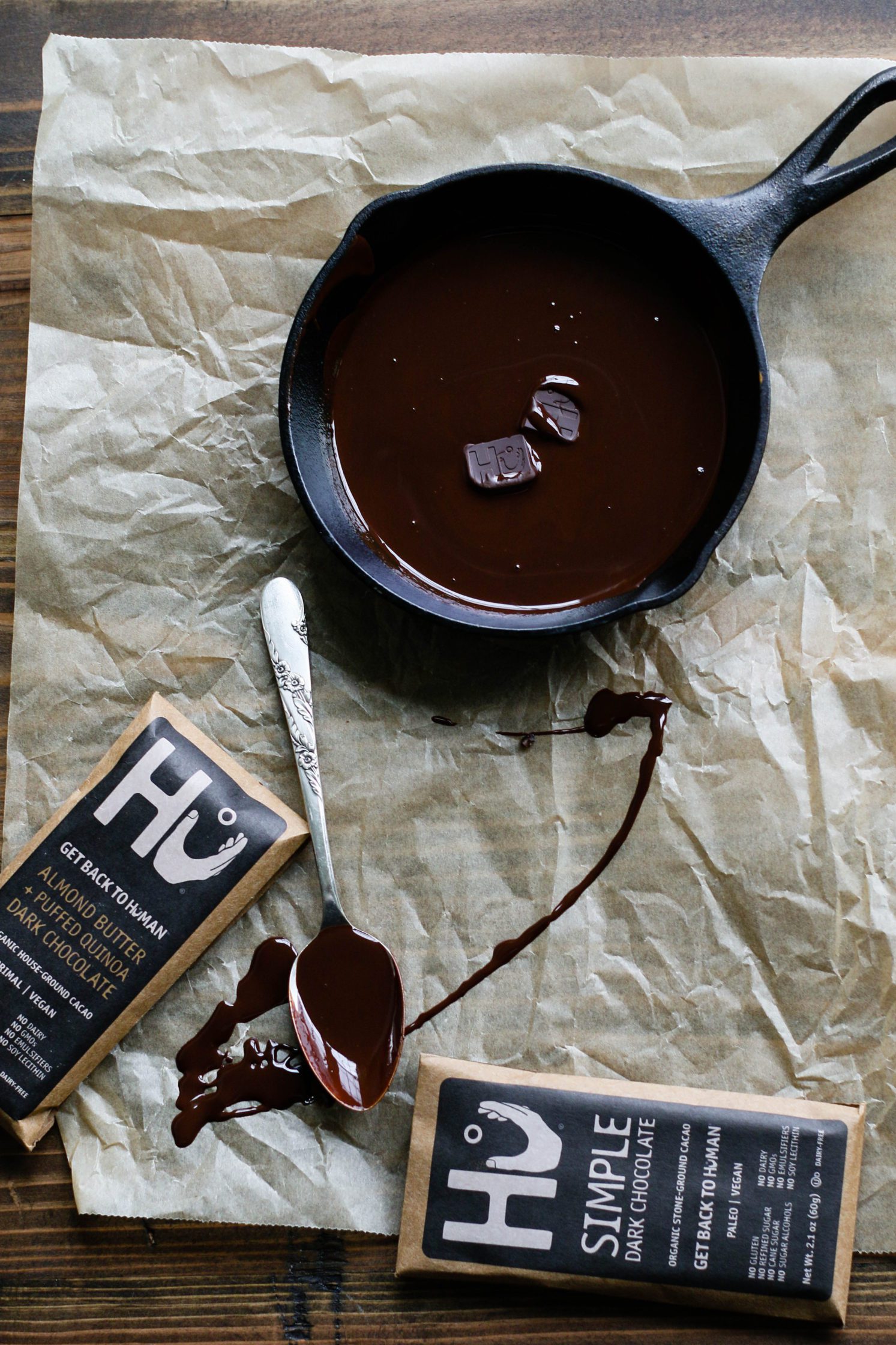 chocolate melted in pan on parchment paper with Hu Kitchen chocolate bar and spoon by Flora & Vino
