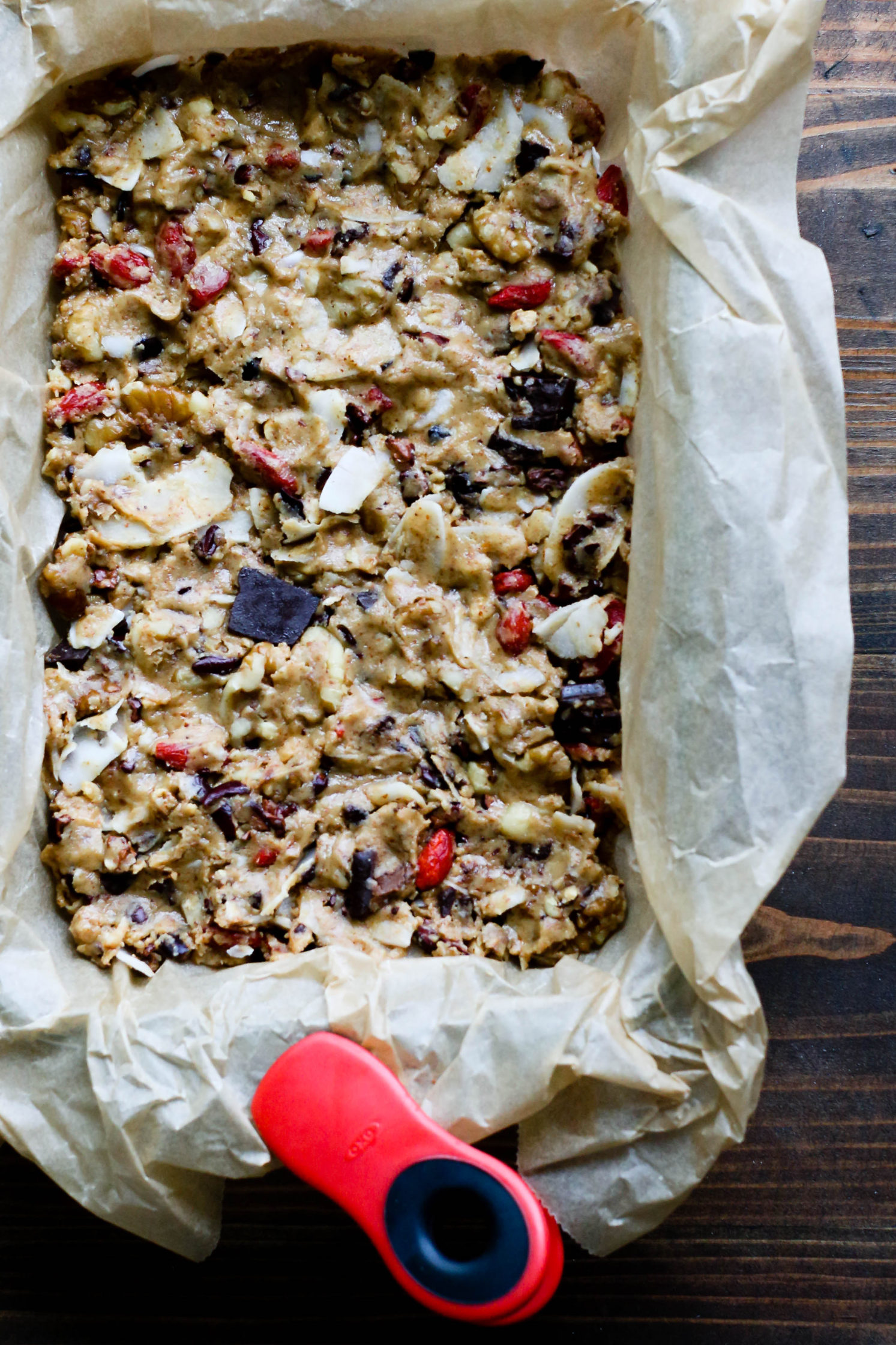 Raw Almond Butter Superfood Bar batter in parchment lined bread pan by Flora & Vino