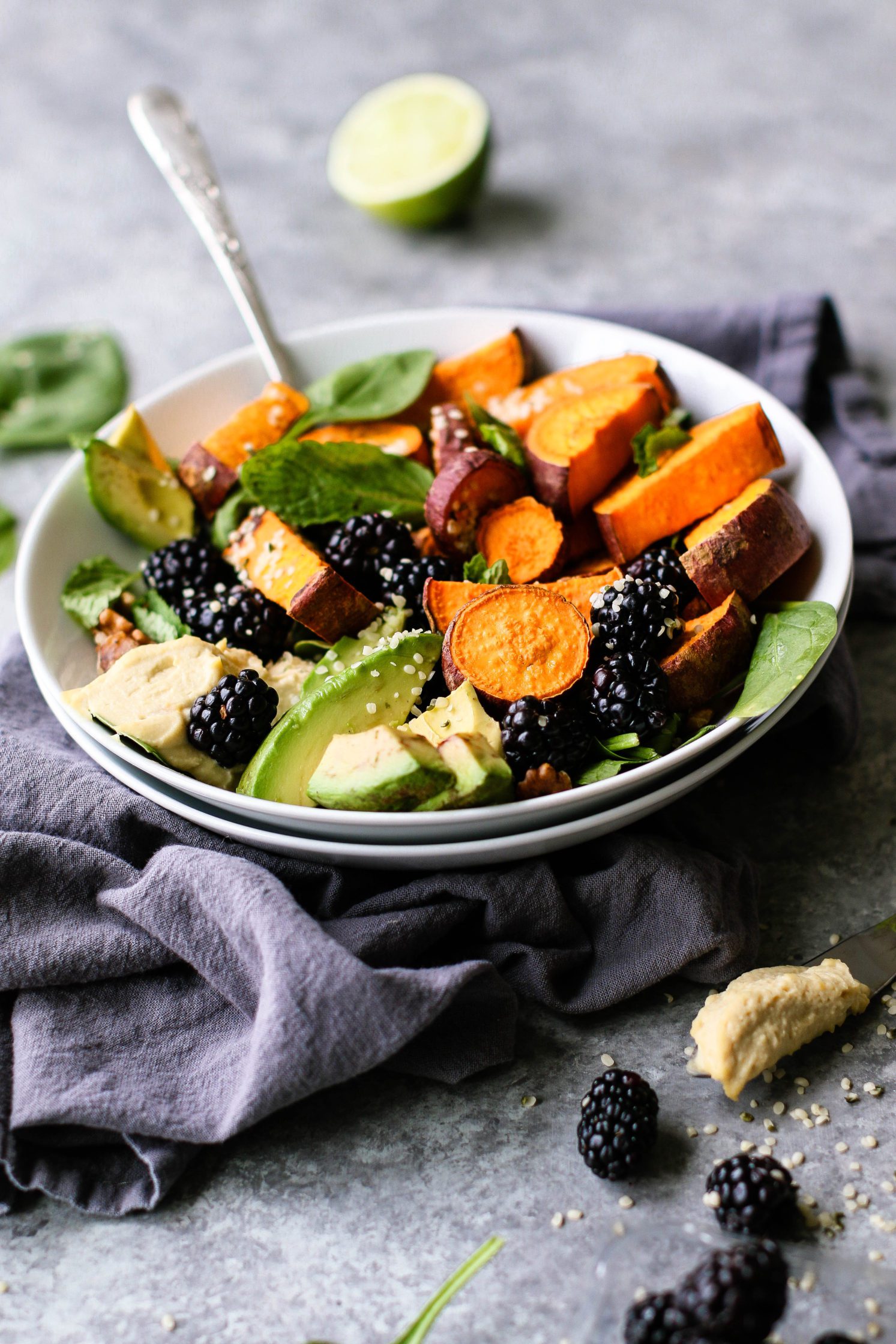 Sweet & Savory Breakfast Salad served in a bowl surrounded by blackberries and spinach leaves 