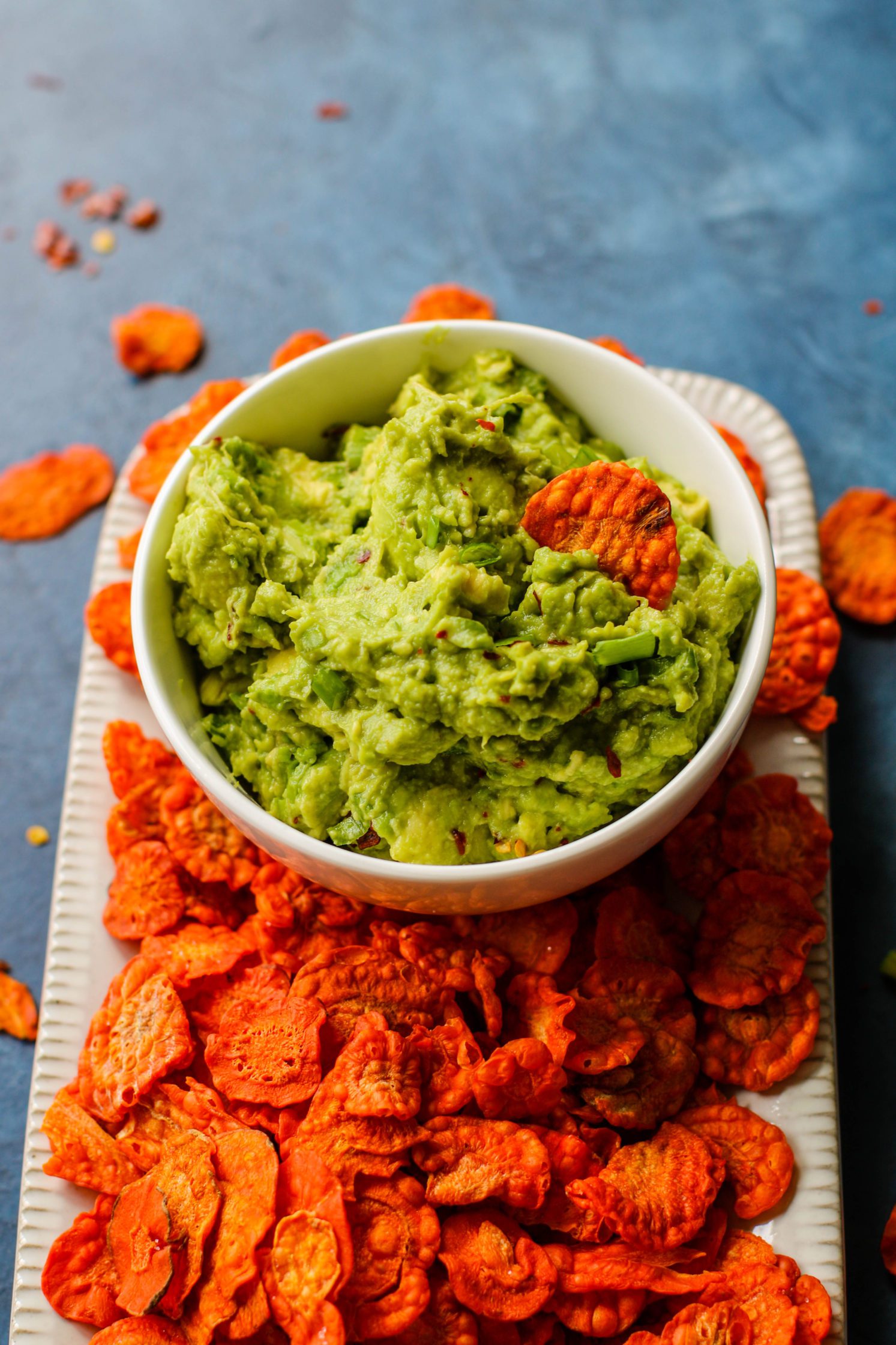 Perfect 5-Ingredient Guacamole served in bowl with carrot chip dipped in by Flora & Vino