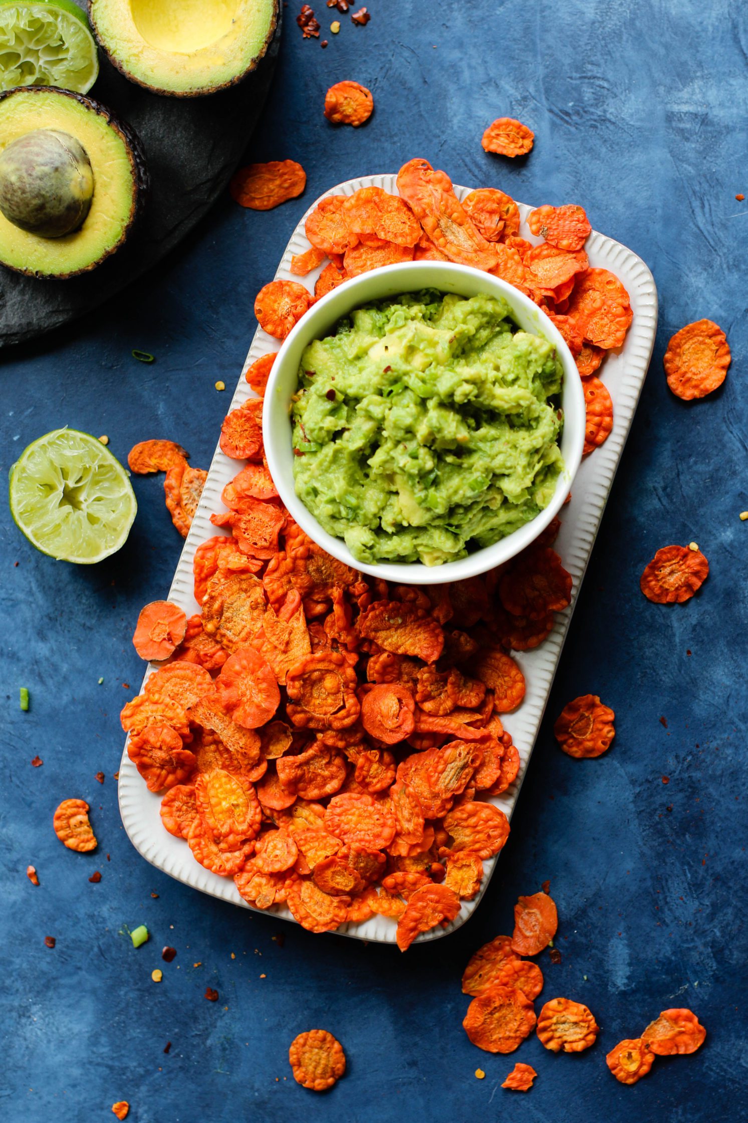 Perfect 5-Ingredient Guacamole in a bowl surrounded by carrot chips by Flora & Vino