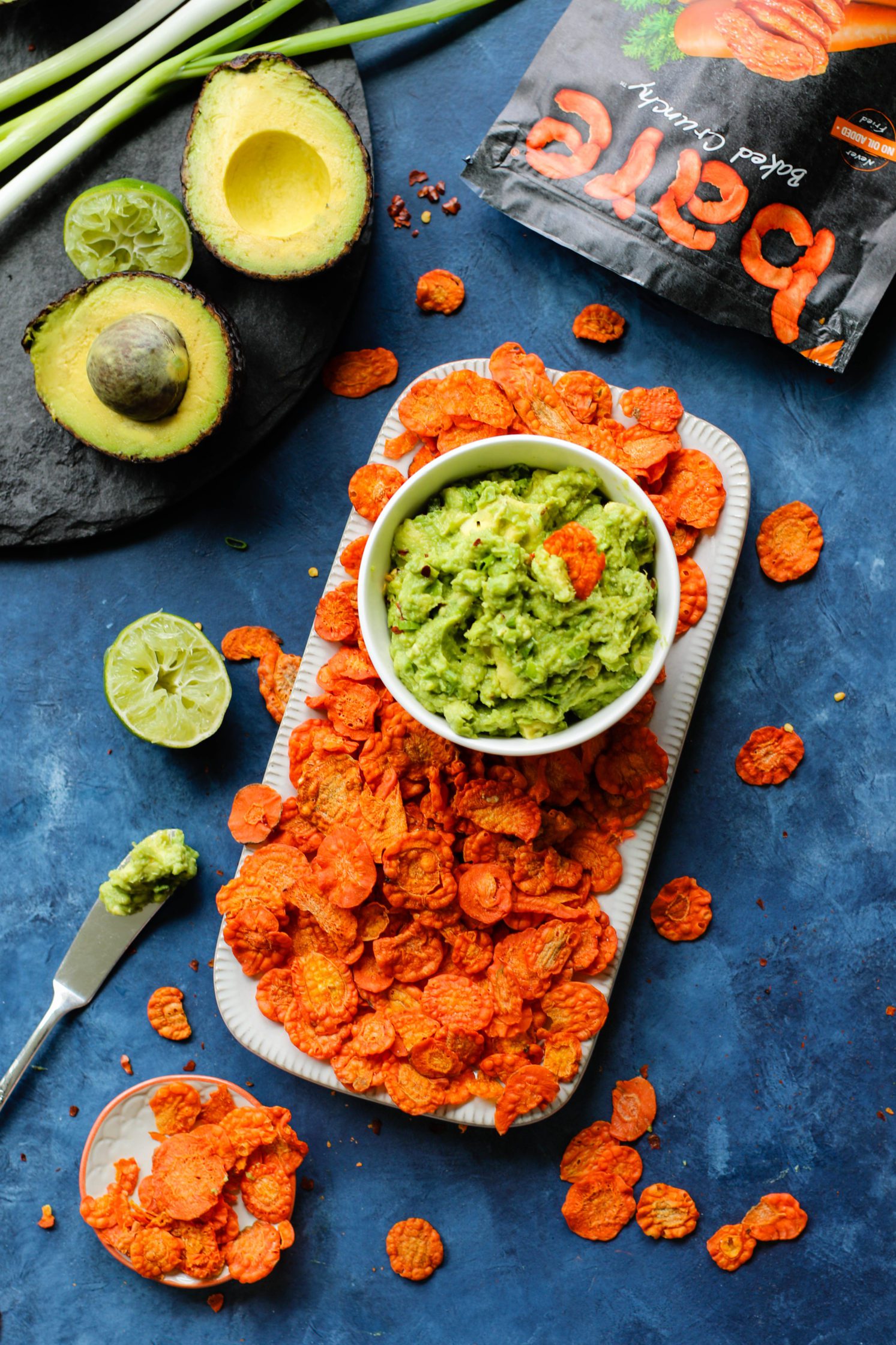 Perfect 5-Ingredient Guacamole served in a bowl with carrot chip dipped in by Flora & Vino 