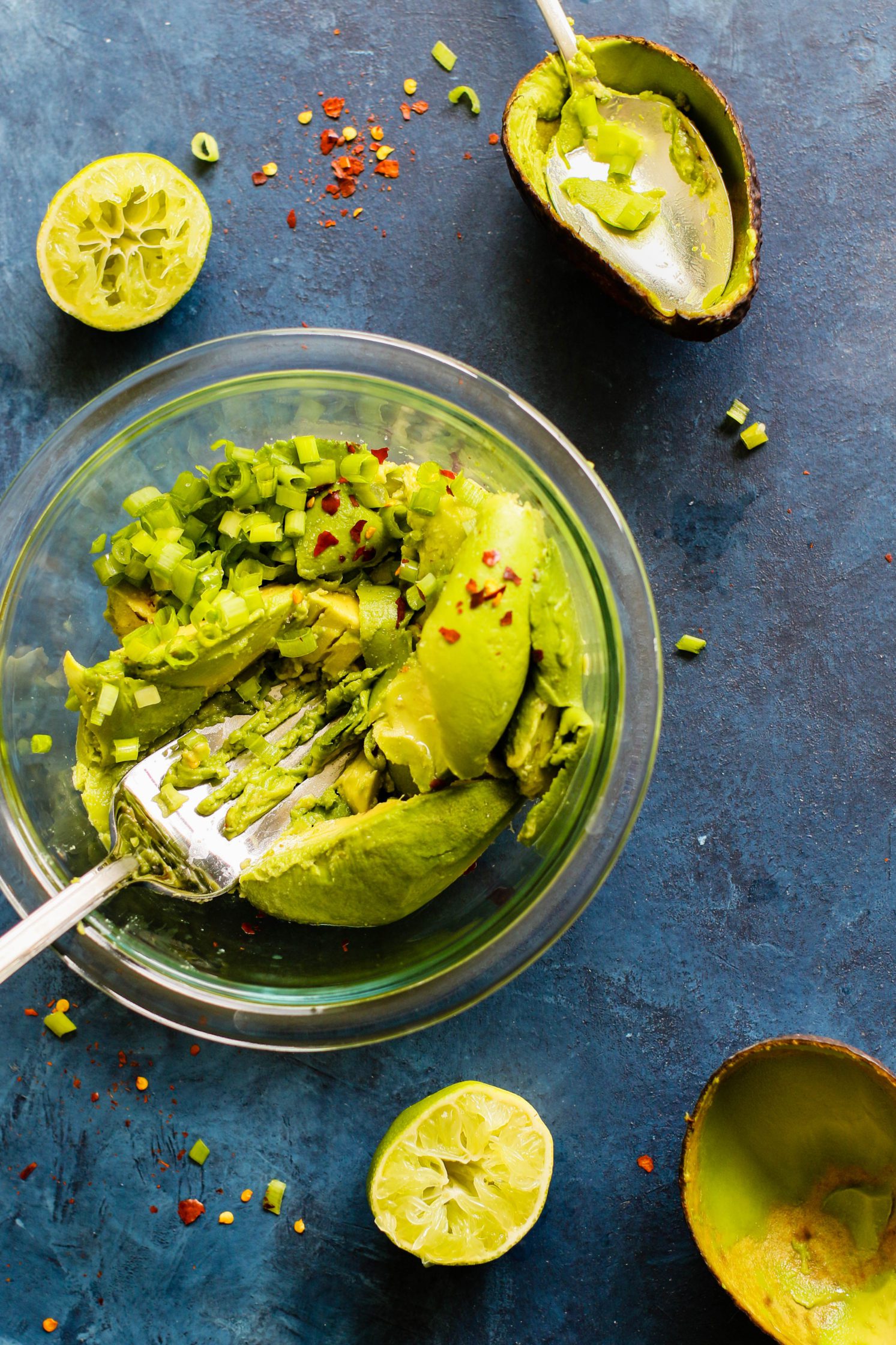 avocados smashed in a bowl with chili flakes and lime by Flora & Vino