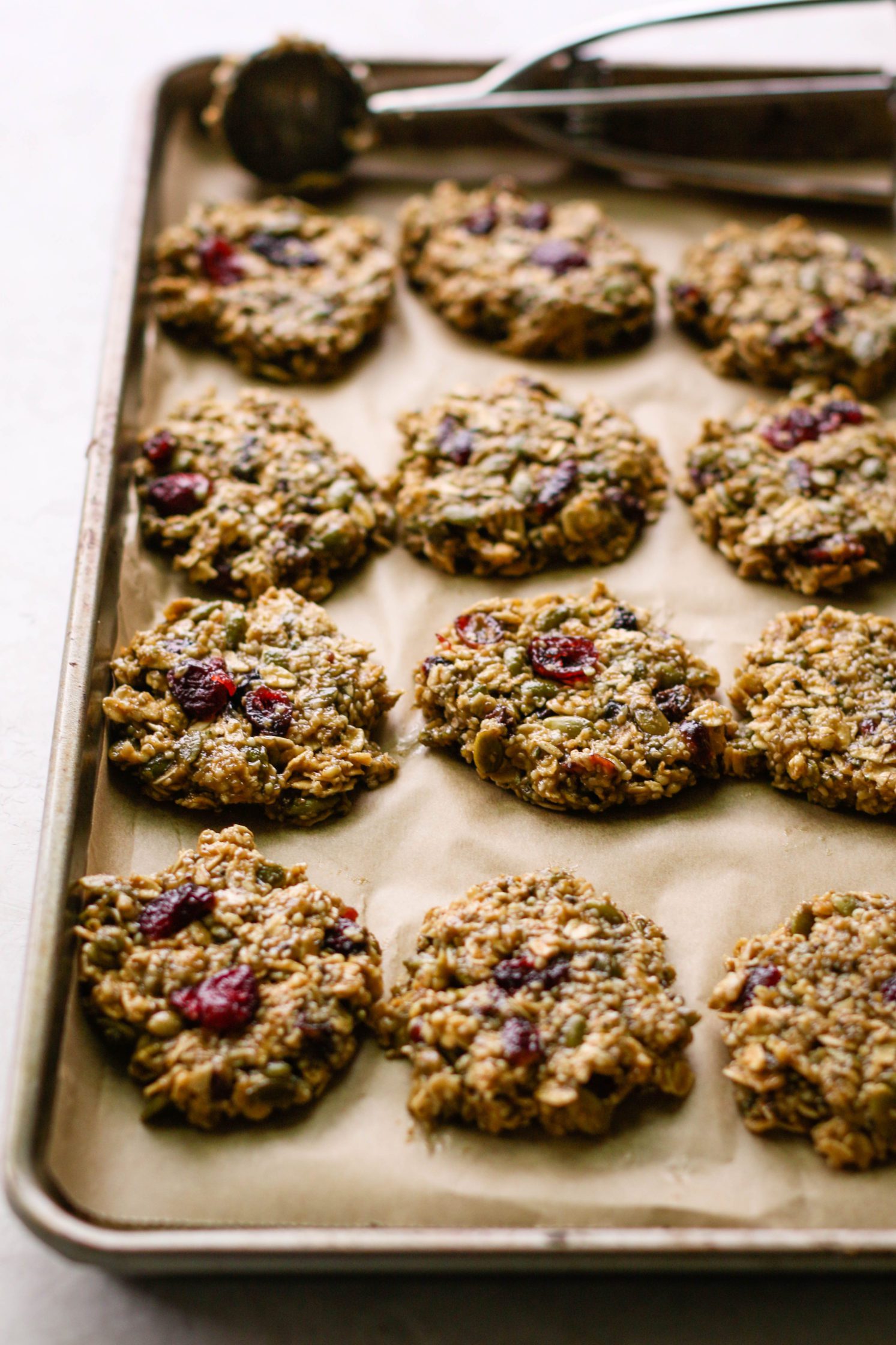 Healthy Trail Mix Cookies formed on parchment lined baking sheet with cookie scoop by Flora & Vino
