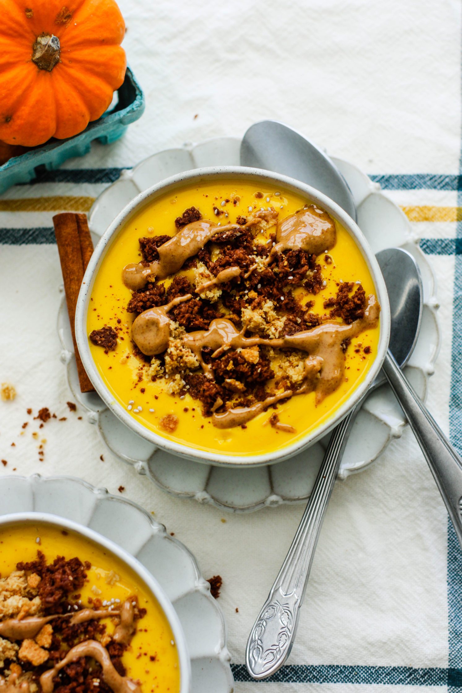 5-Minute Pumpkin Yogurt Bowl served in bowls with spoons and pumpkin in background by Flora & Vino