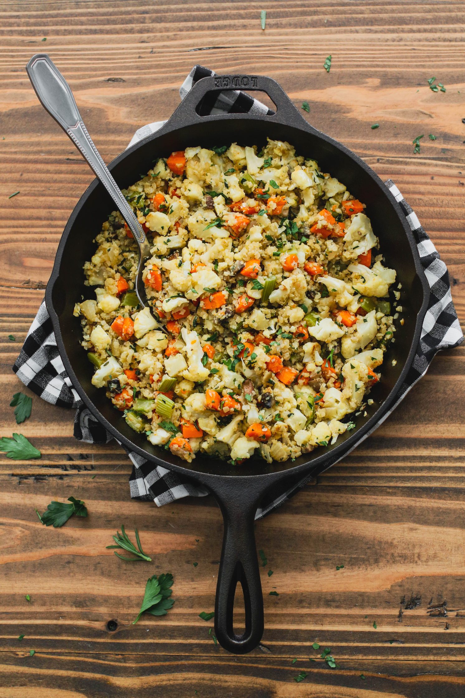 Stovetop Cauliflower Rice Stuffing served in a cast iron skillet with a spoon by Flora & Vino
