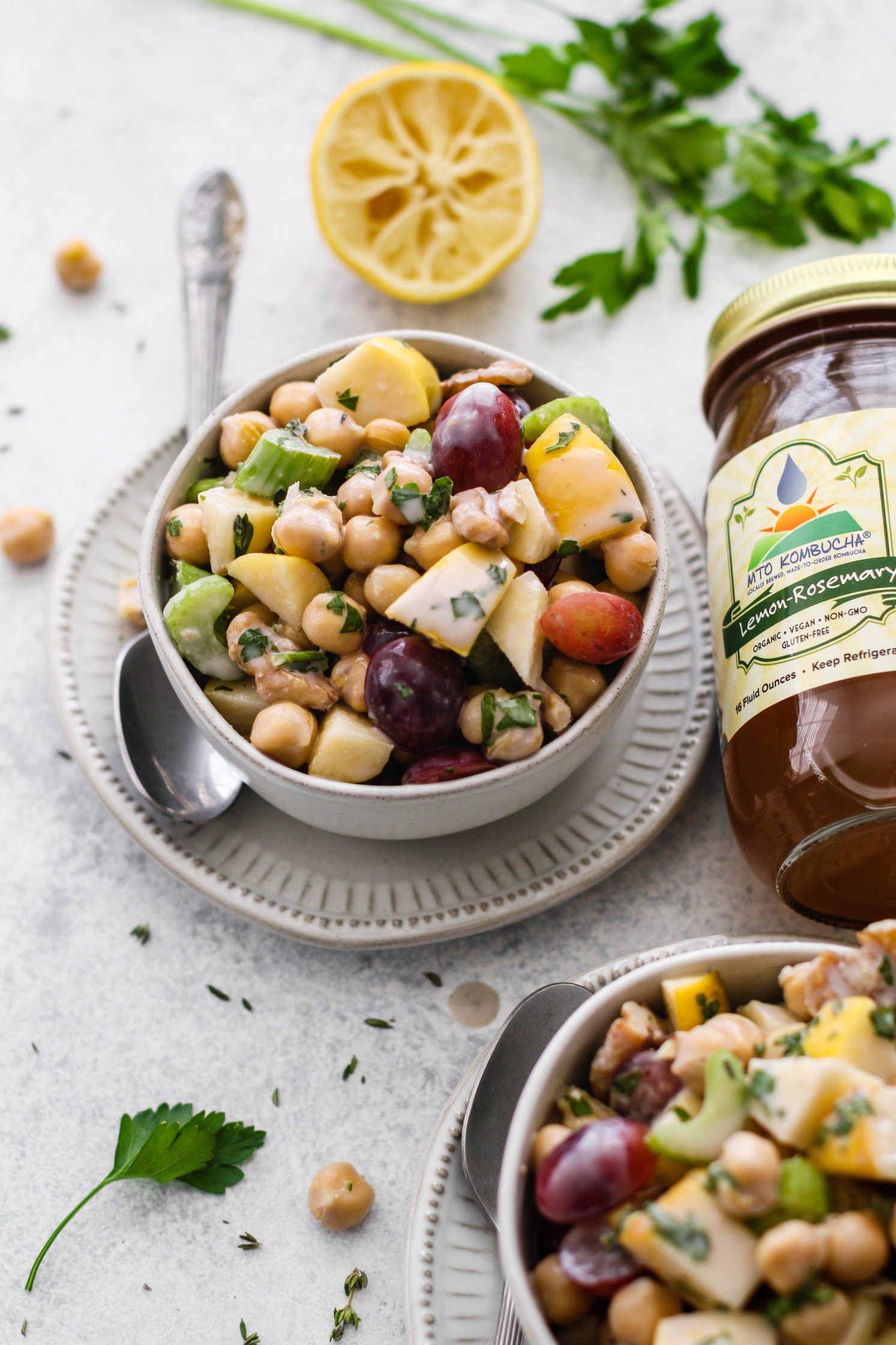 Chickpea Waldorf Salad with Creamy Kombucha Dressing in bowls topped with parsley with lemon on the side