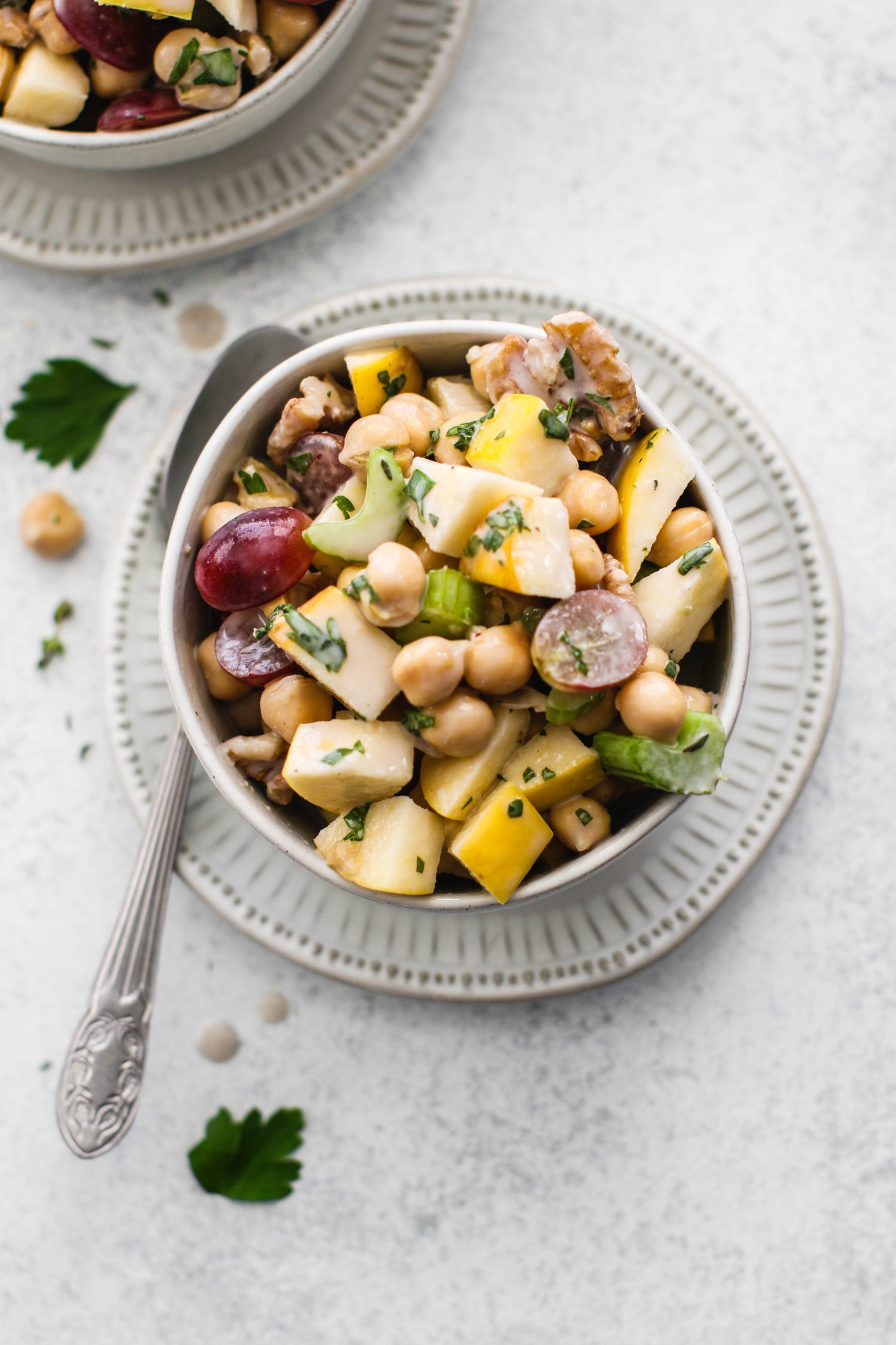 Chickpea Waldorf Salad with Creamy Kombucha Dressing in bowls topped with parsley with lemon on the side
