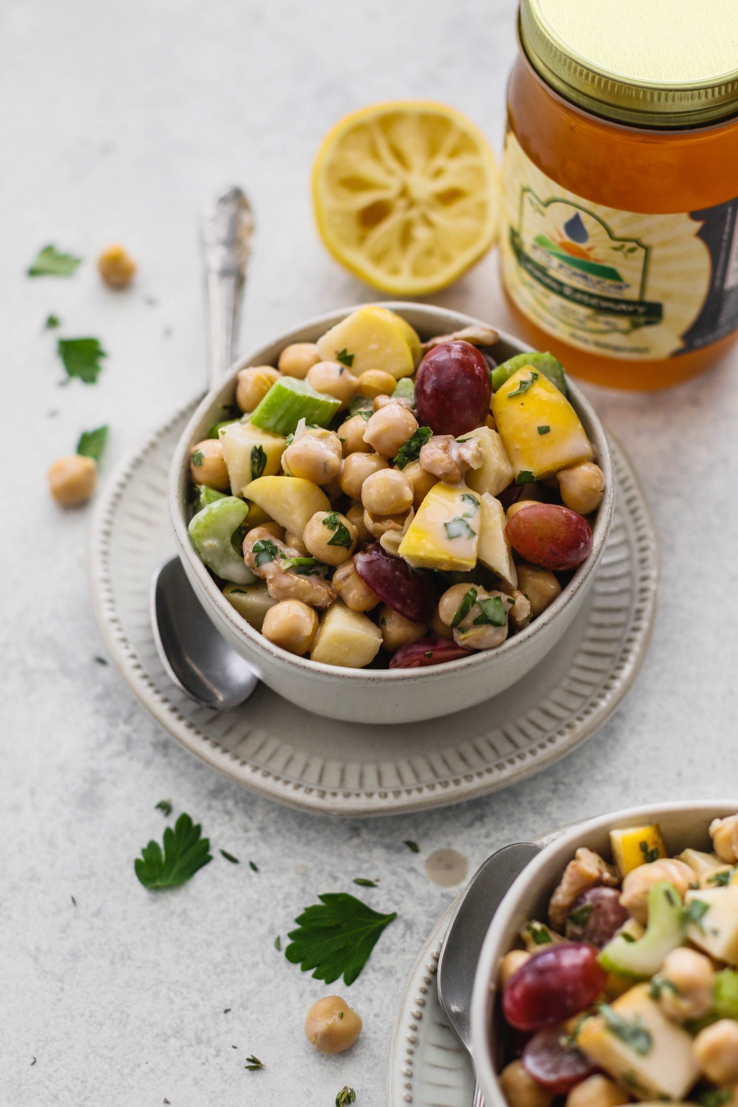Chickpea Waldorf Salad with Creamy Kombucha Dressing in bowls topped with parsley with lemon on the side