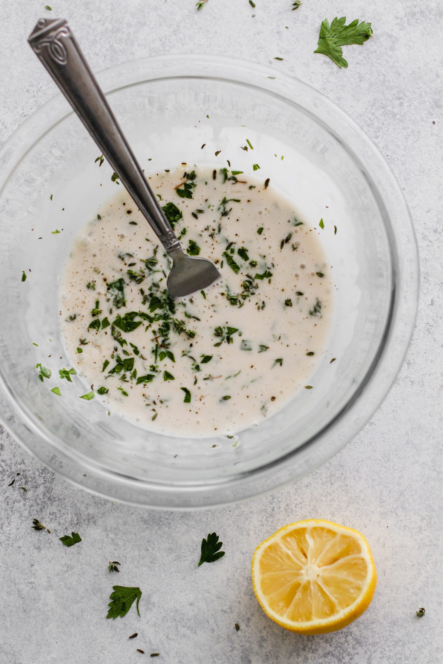 creamy kombucha dressing in bowl topped with parsley and fork 