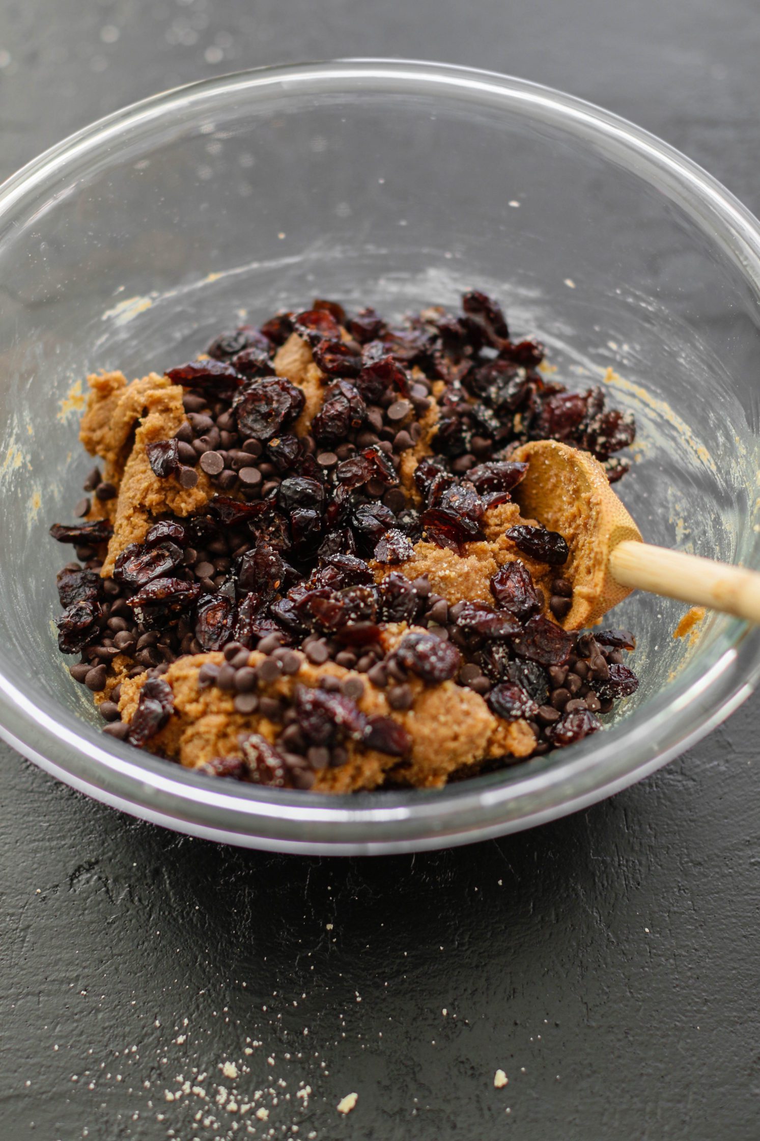 Cranberry Chocolate Chip Cookie batter in a bowl with wooden spoon by Flora & Vino