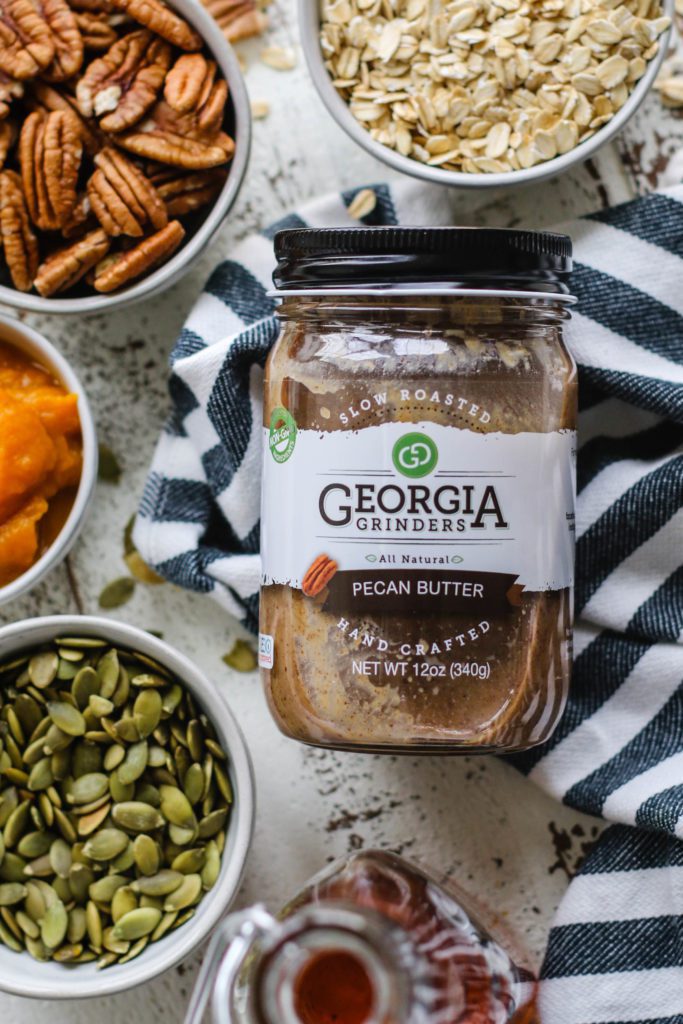 Georgia Grinders Pecan Butter surrounded by granola ingredients on towel by Flora & Vino