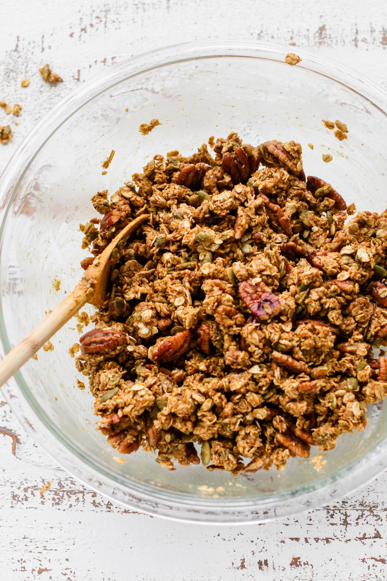 Pumpkin Spice Pecan Granola wet and mixed in glass bowl with spoon by Flora & Vino