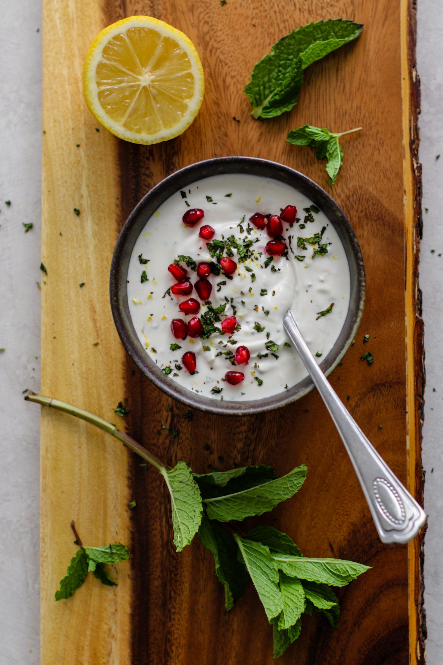 herbed yogurt sauce in a bowl topped with pomegranate by Flora & Vino
